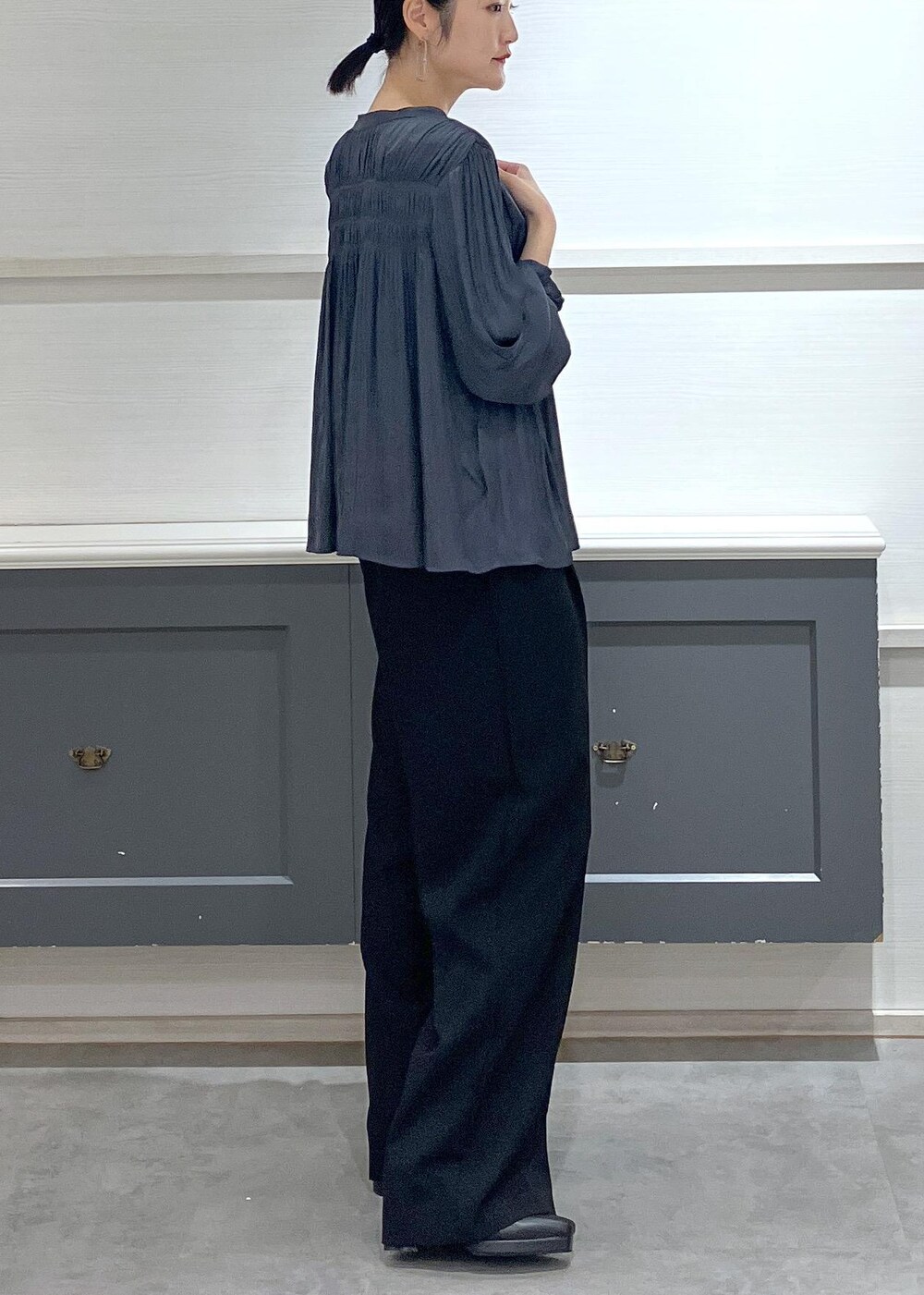 ホワイト系のキャミソール、グレー系のショルダーバッグ、ブラック系のスラックスを着用したレディースの秋コーディネートの2枚目の写真