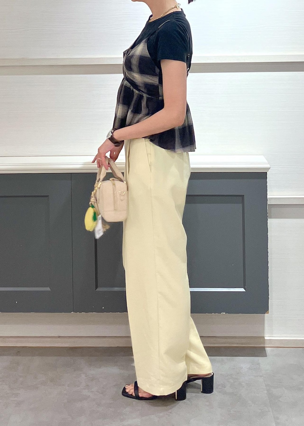 ブラック系のサンダル、イエロー系のスラックス、ブラック系のTシャツ/カットソーを着用したレディースの夏コーディネートの2枚目の写真