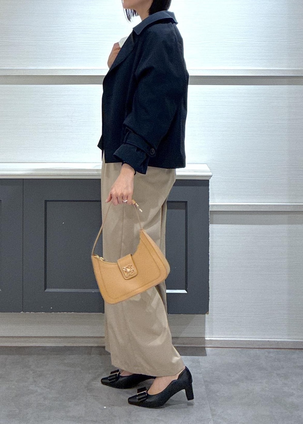イエロー系のショルダーバッグ、ブラック系のパンプス、ブルー系のトレンチコートを着用したレディースの春コーディネートの5枚目の写真