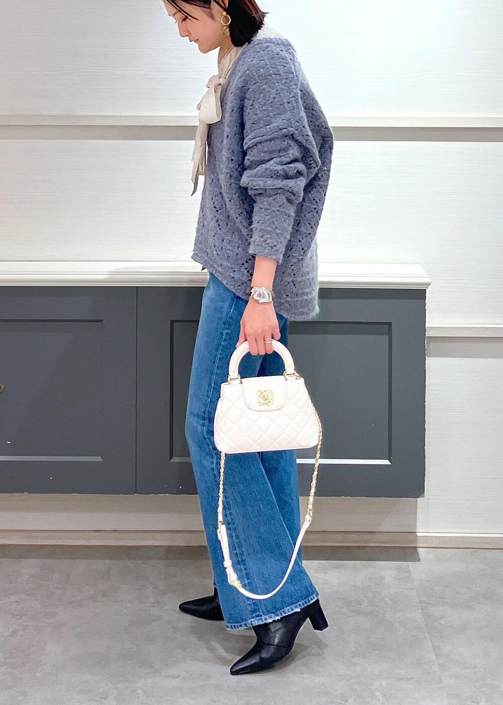 ブラック系のブーツ、ホワイト系のシャツ/ブラウス、ブルー系のニット/セーターを着用したレディースの冬コーディネートの2枚目の写真