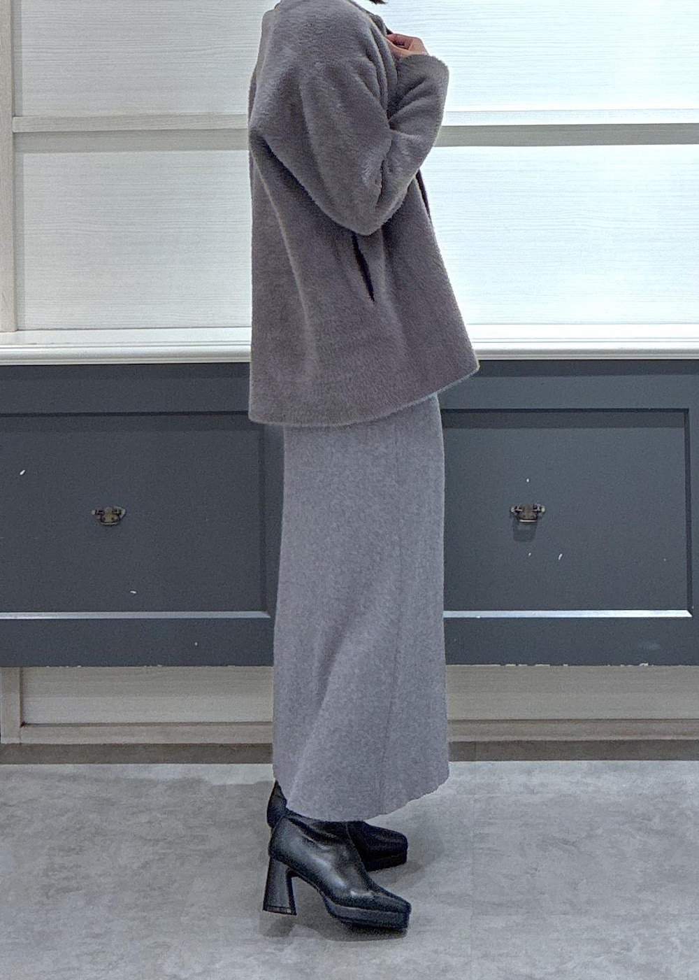 ブラック系のショルダーバッグ、ブラック系のブーツ、グレー系のスカートを着用したレディースの秋コーディネートの4枚目の写真