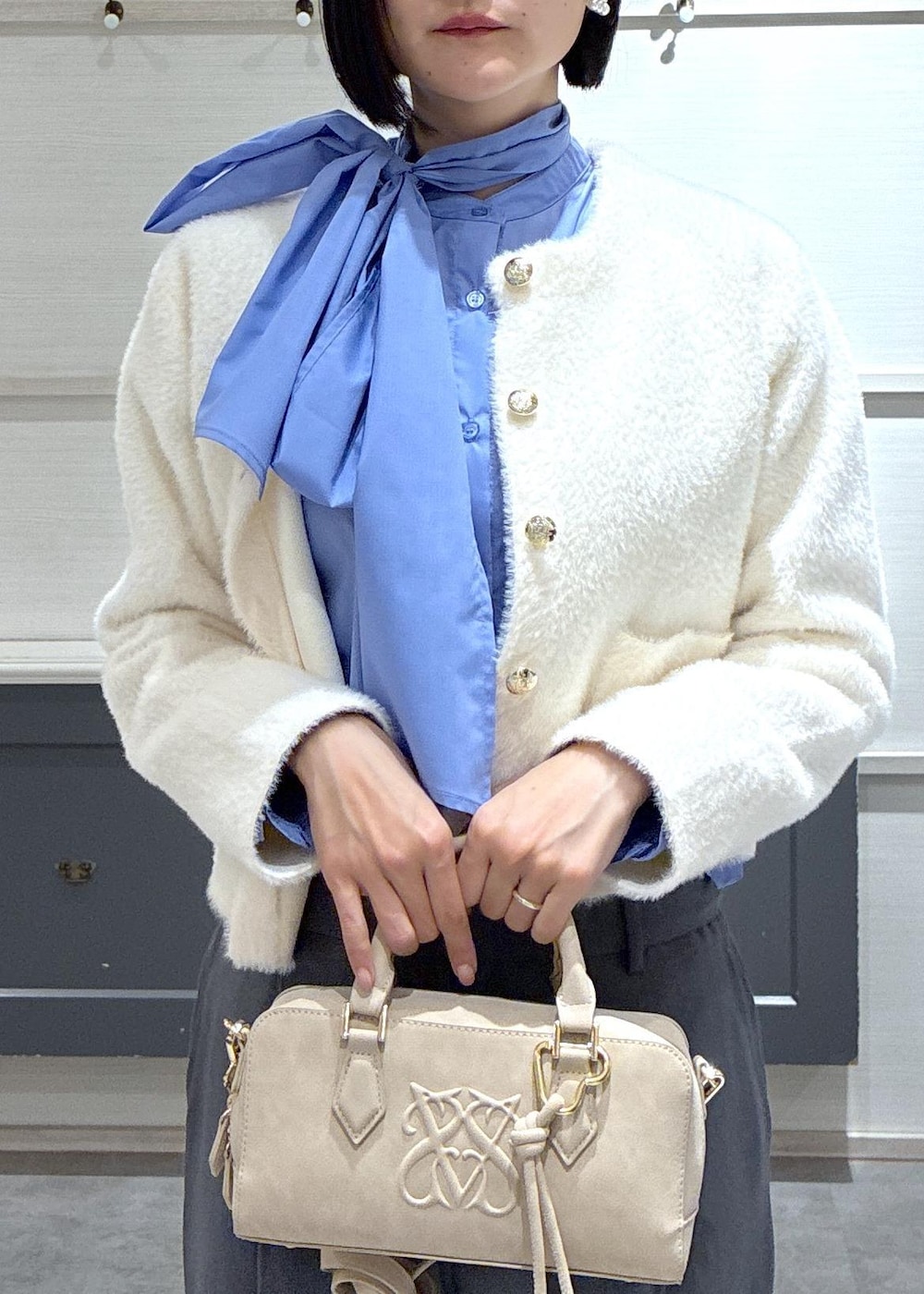 ピンク系のボストンバッグ、グレー系のスラックス、ホワイト系のカーディガン/ボレロを着用したレディースの冬コーディネートの5枚目の写真