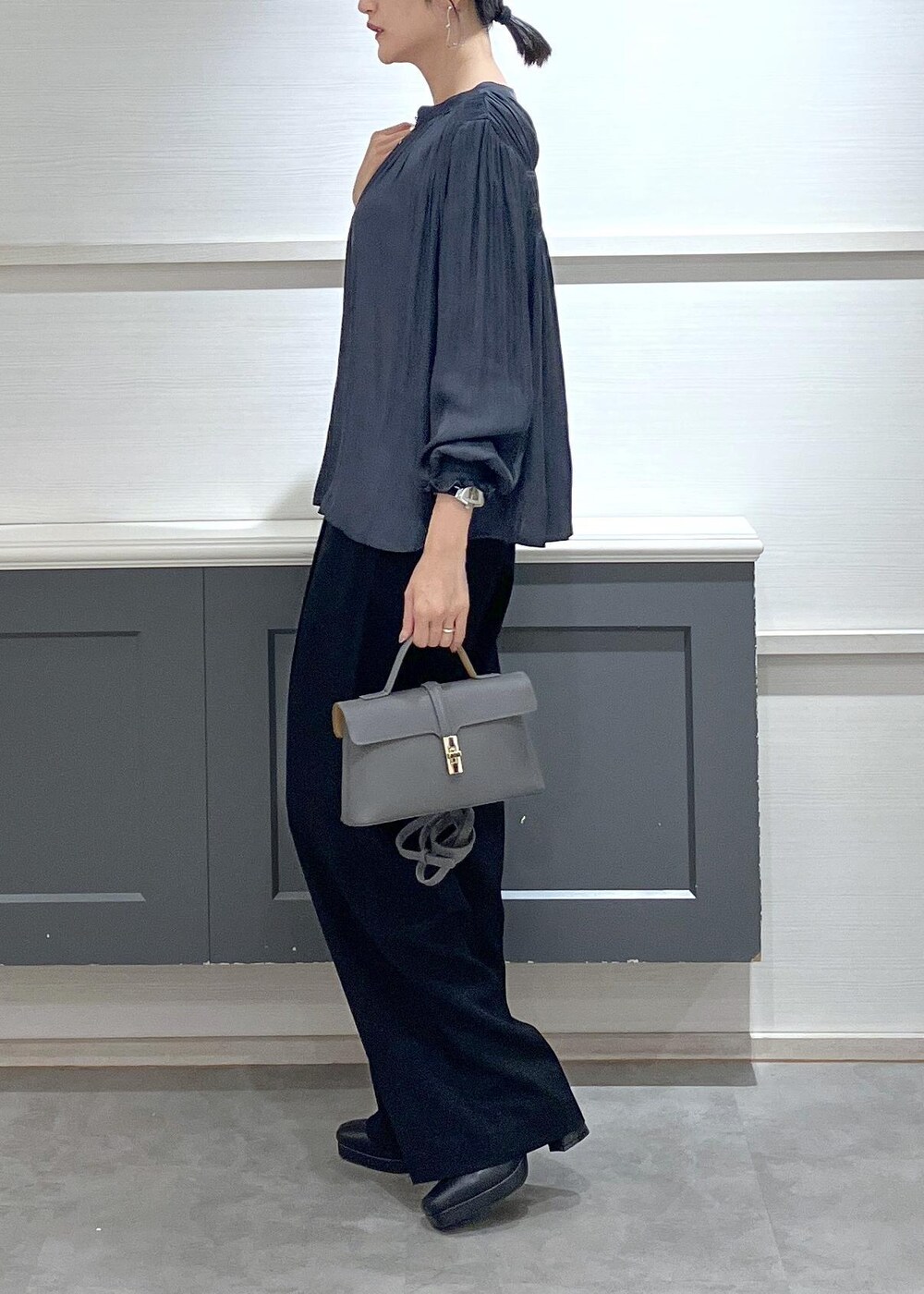 ホワイト系のキャミソール、グレー系のショルダーバッグ、ブラック系のスラックスを着用したレディースの秋コーディネートの3枚目の写真