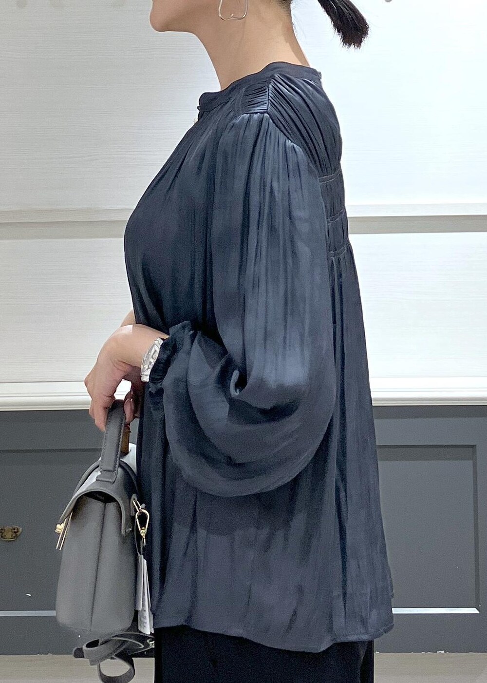 ホワイト系のキャミソール、グレー系のショルダーバッグ、ブラック系のスラックスを着用したレディースの秋コーディネートの7枚目の写真