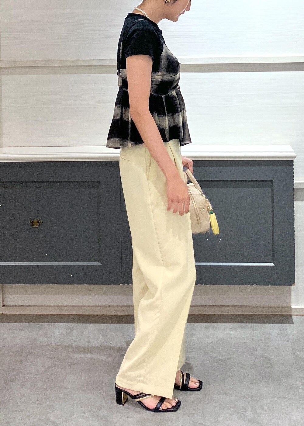 ブラック系のサンダル、イエロー系のスラックス、ブラック系のTシャツ/カットソーを着用したレディースの夏コーディネートの3枚目の写真