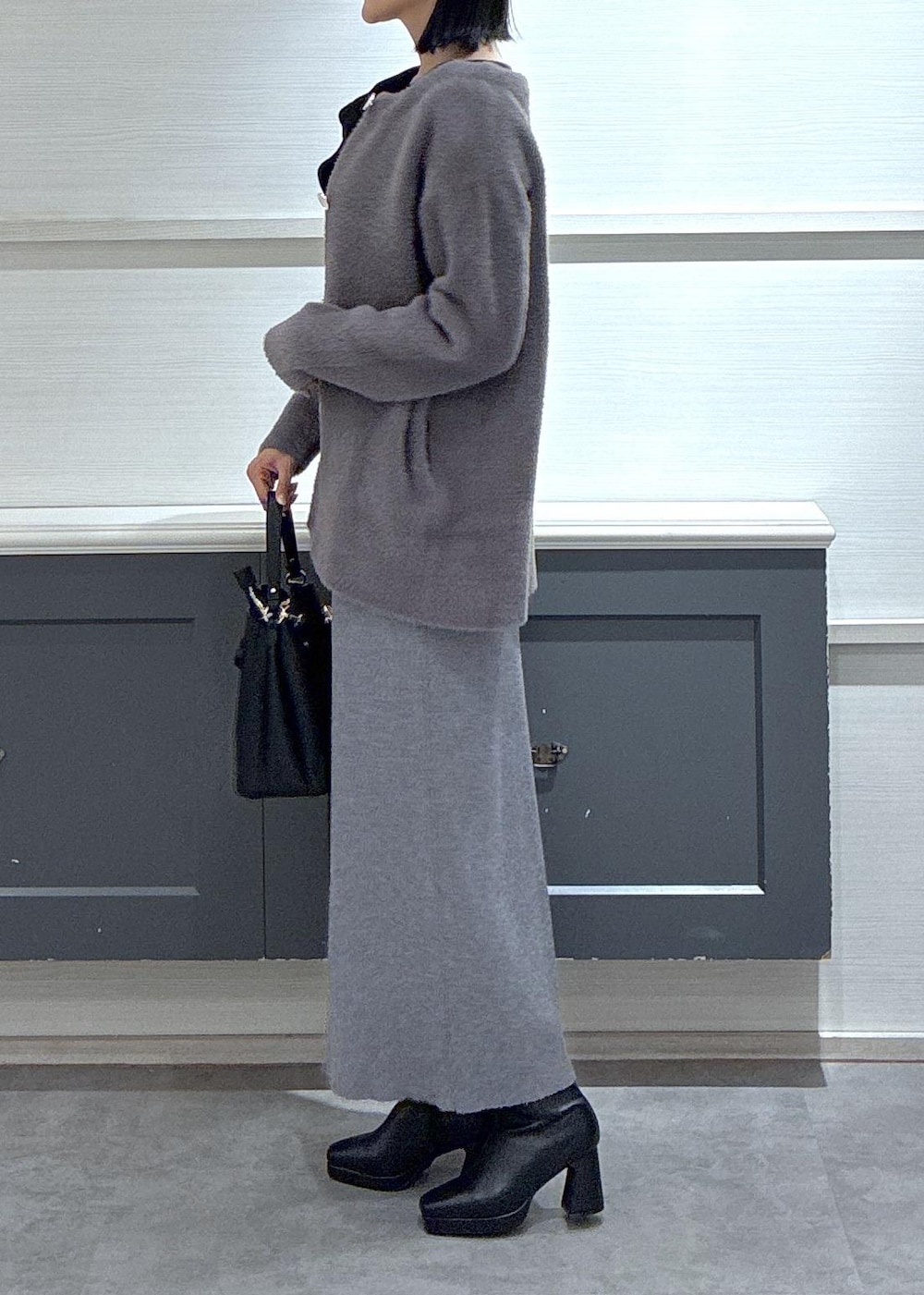 ブラック系のショルダーバッグ、ブラック系のブーツ、グレー系のスカートを着用したレディースの秋コーディネートの5枚目の写真