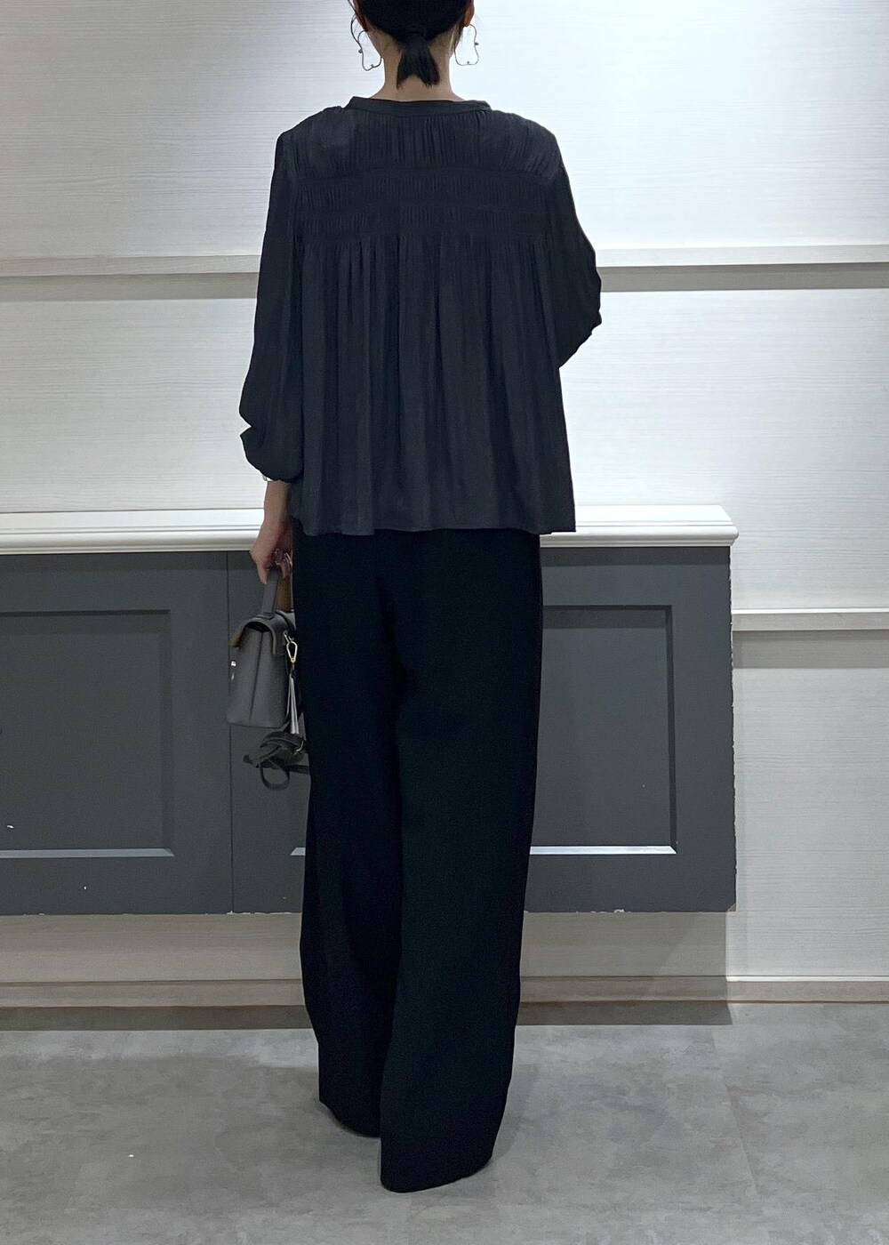 ホワイト系のキャミソール、グレー系のショルダーバッグ、ブラック系のスラックスを着用したレディースの秋コーディネートの4枚目の写真