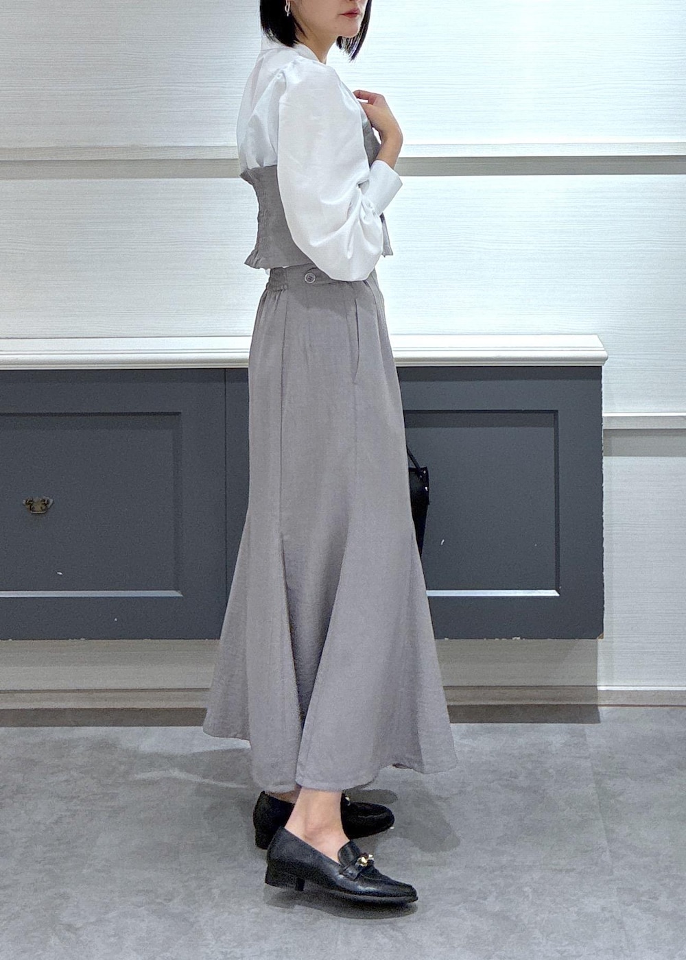 ブラック系のショルダーバッグ、ブラック系のローファー、グレー系のスカートを着用したレディースの春コーディネートの3枚目の写真