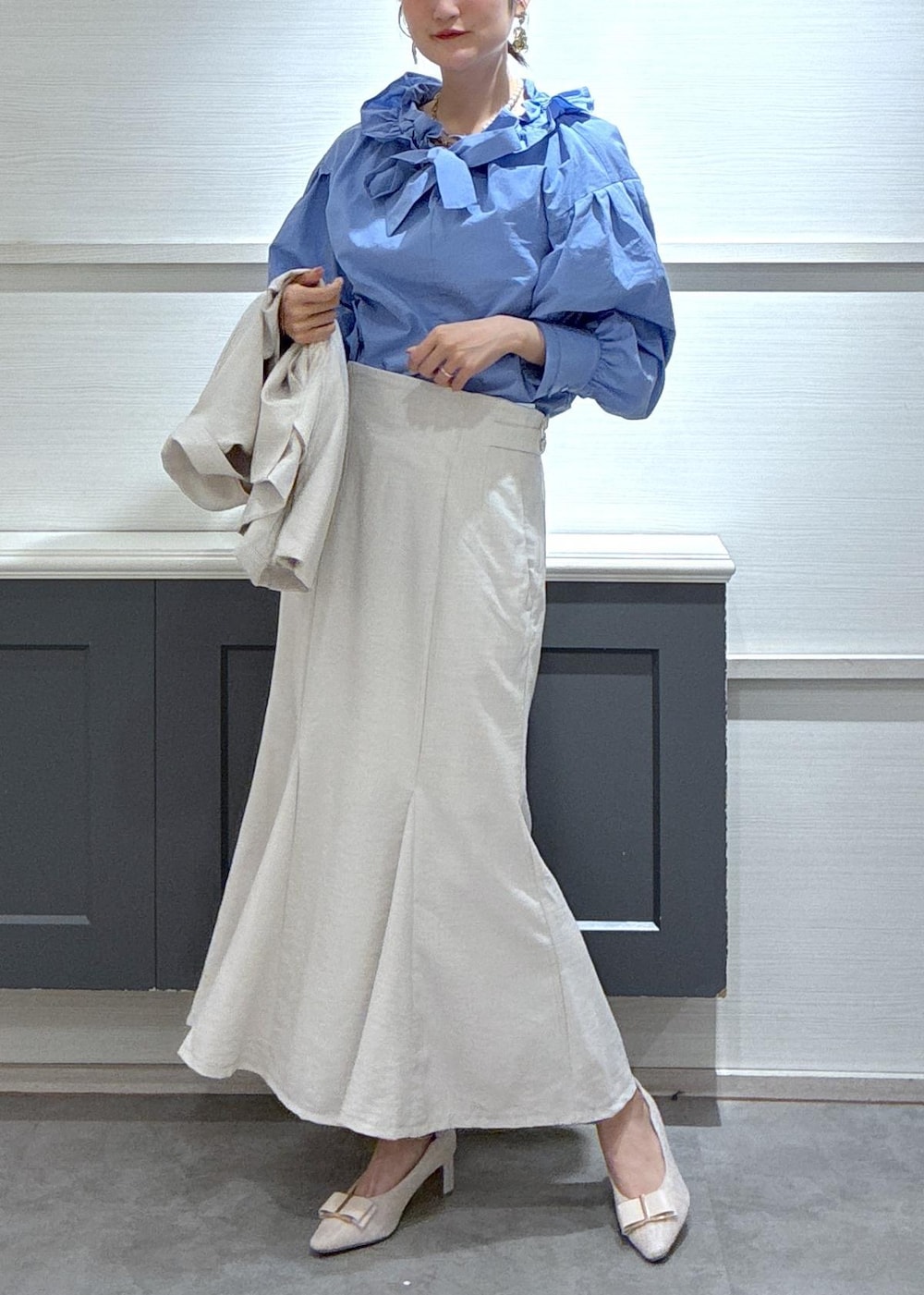 ホワイト系のショルダーバッグ、ベージュ系のパンプス、ブルー系のシャツ/ブラウスを着用したレディースの春コーディネートの2枚目の写真