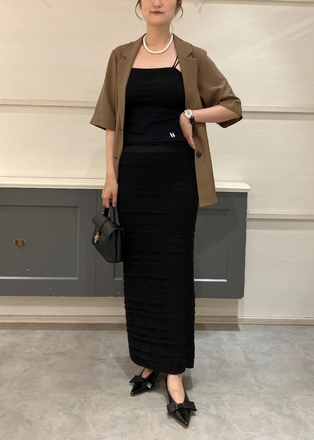 ブラック系のショルダーバッグ、ブラック系のパンプス、ブラック系のキャミソールを着用したレディースの夏コーディネートの2枚目の写真