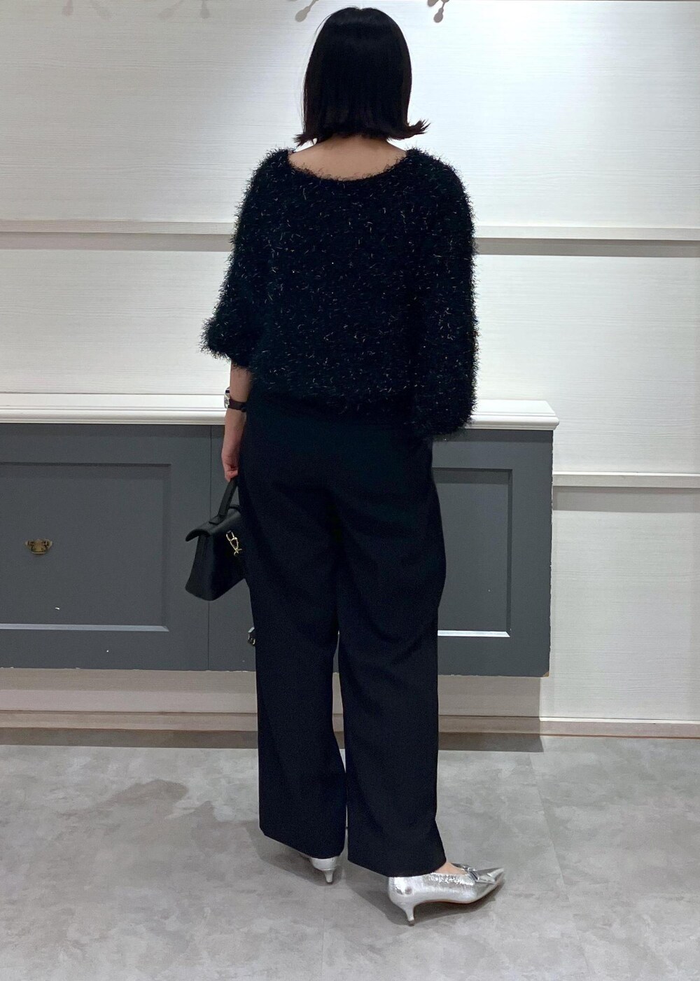 シルバー系のパンプス、ブラック系のショルダーバッグ、ブラック系のスラックスを着用したレディースの冬コーディネートの4枚目の写真