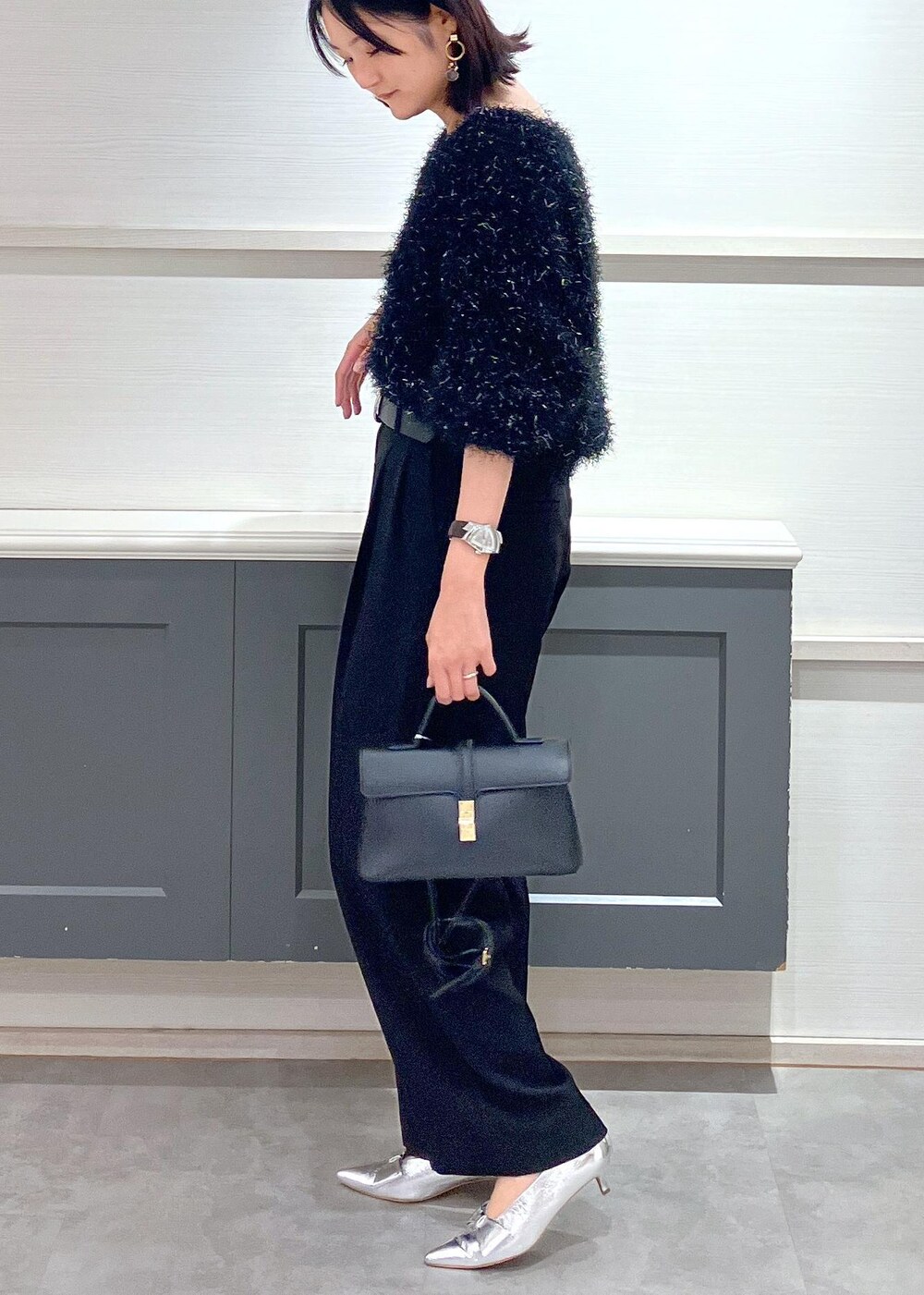 シルバー系のパンプス、ブラック系のショルダーバッグ、ブラック系のスラックスを着用したレディースの冬コーディネートの2枚目の写真