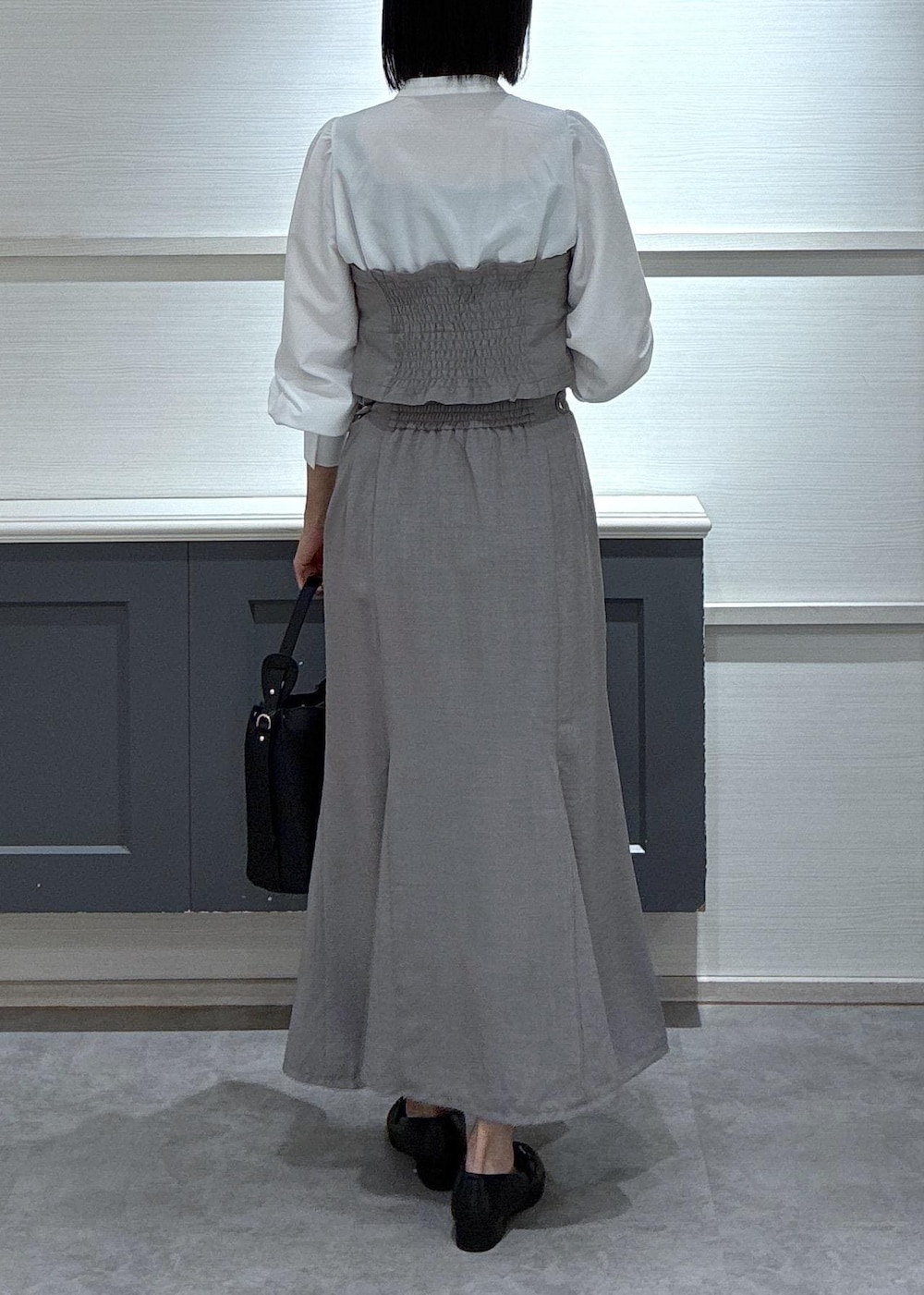 ブラック系のショルダーバッグ、ブラック系のローファー、グレー系のスカートを着用したレディースの春コーディネートの5枚目の写真