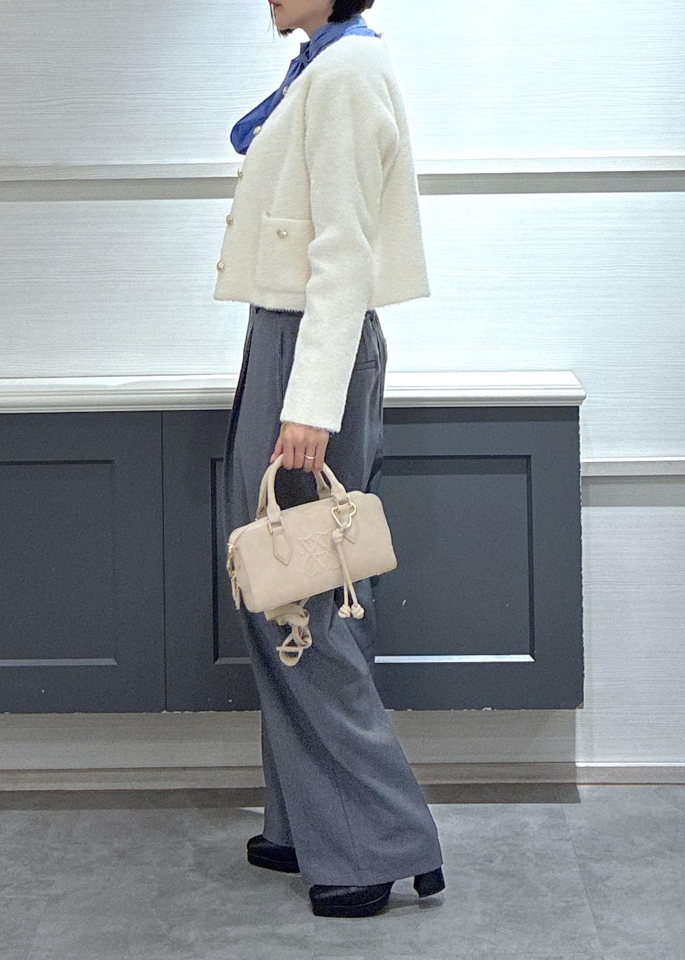 ピンク系のボストンバッグ、グレー系のスラックス、ホワイト系のカーディガン/ボレロを着用したレディースの冬コーディネートの2枚目の写真