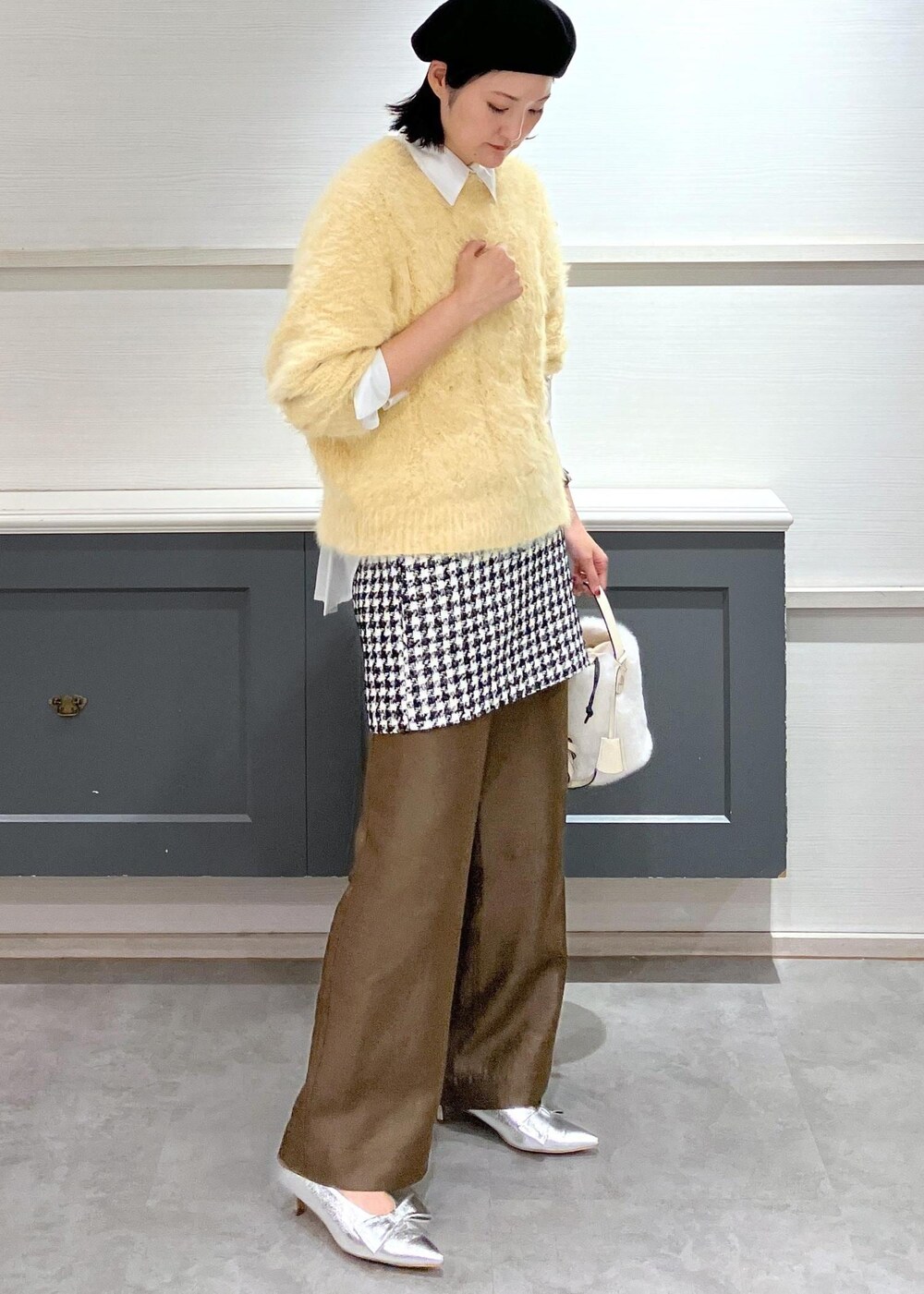 シルバー系のパンプス、ブラック系のスカート、ホワイト系のシャツ/ブラウスを着用したレディースの冬コーディネートの2枚目の写真