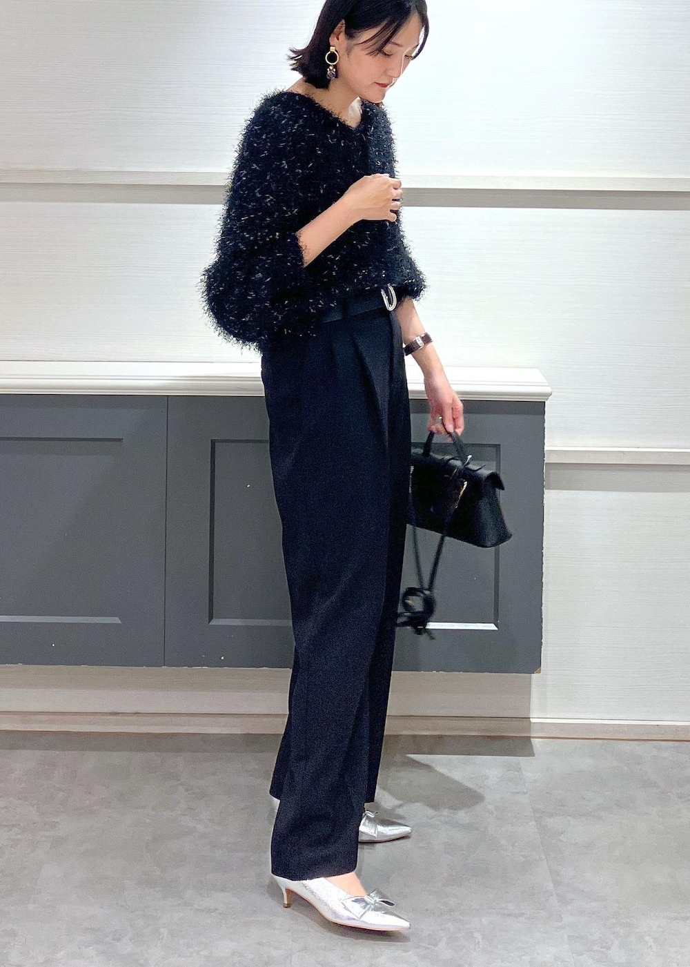 シルバー系のパンプス、ブラック系のショルダーバッグ、ブラック系のスラックスを着用したレディースの冬コーディネートの3枚目の写真