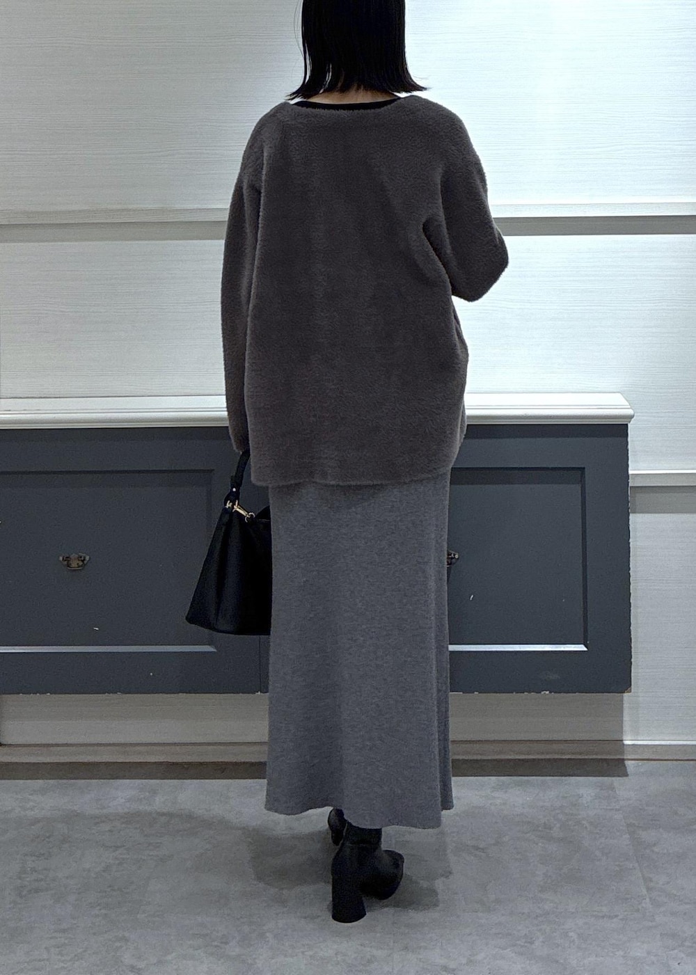 ブラック系のショルダーバッグ、ブラック系のブーツ、グレー系のスカートを着用したレディースの秋コーディネートの10枚目の写真