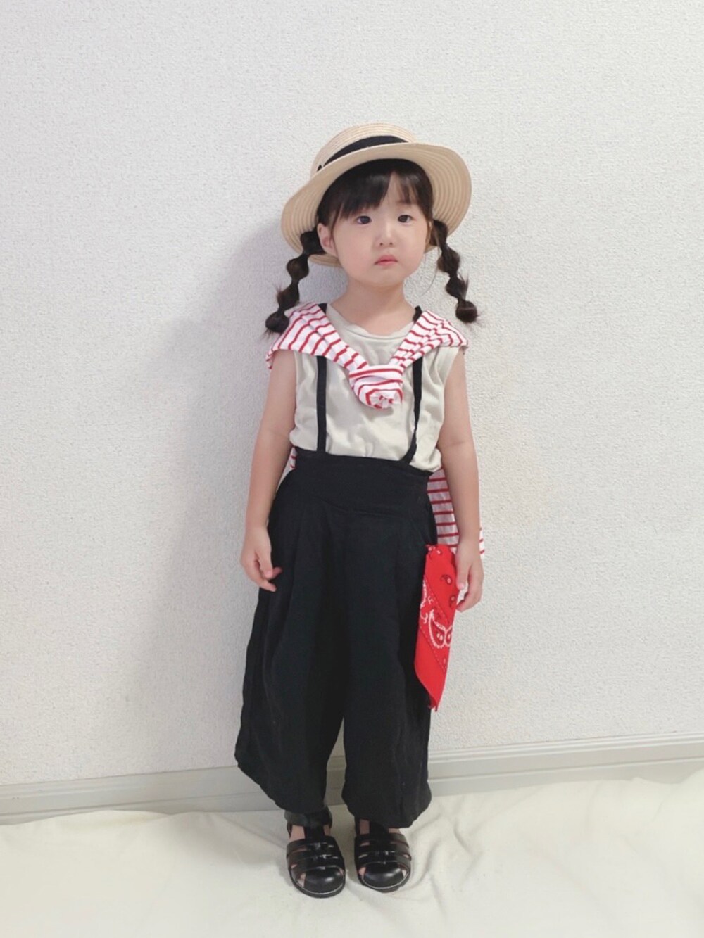 レッド系のTシャツ/カットソー、ブラック系のサロペット/オーバーオール、ブラック系のサンダルを着用したキッズの秋コーディネートの2枚目の写真