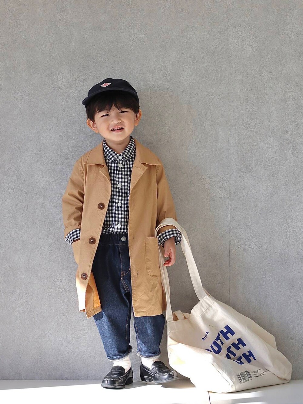 ホワイト系のトートバッグ、ベージュ系のステンカラーコート、ブラック系のシャツ/ブラウスを着用したキッズの秋コーディネートの2枚目の写真