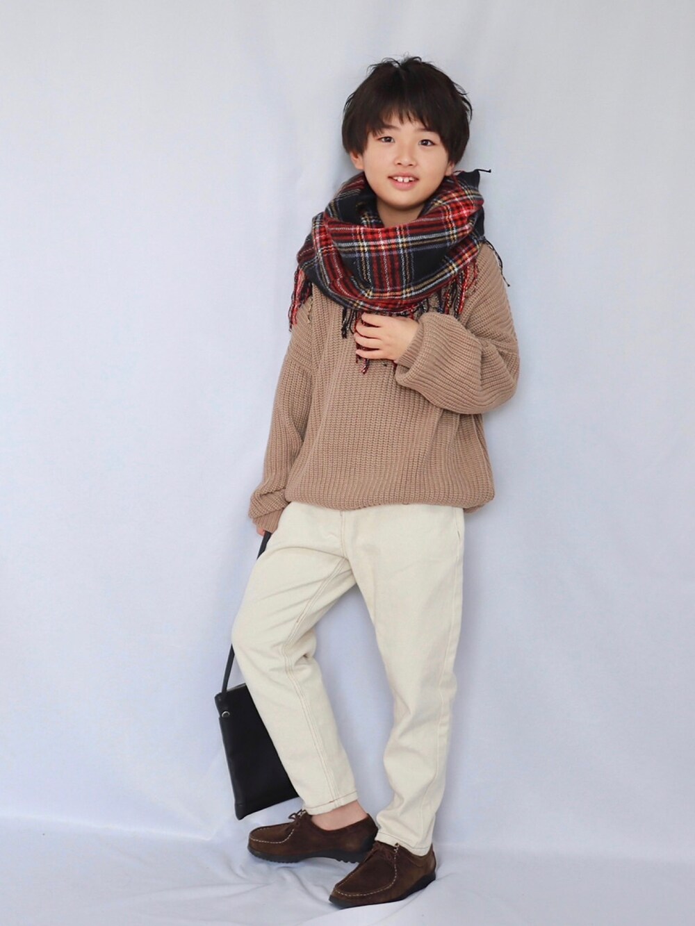 ブラウン系のニット/セーター、ベージュ系のデニムパンツ、ブラック系のトートバッグを着用したキッズの冬コーディネートの2枚目の写真