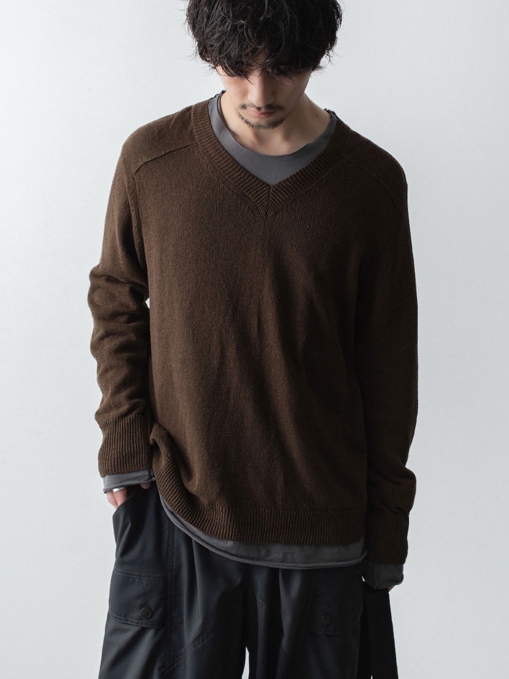 ブラウン系のニット/セーター、グレー系のTシャツ/カットソー、ブラック系のボディバッグ/ウエストポーチを着用したメンズの春コーディネートの2枚目の写真