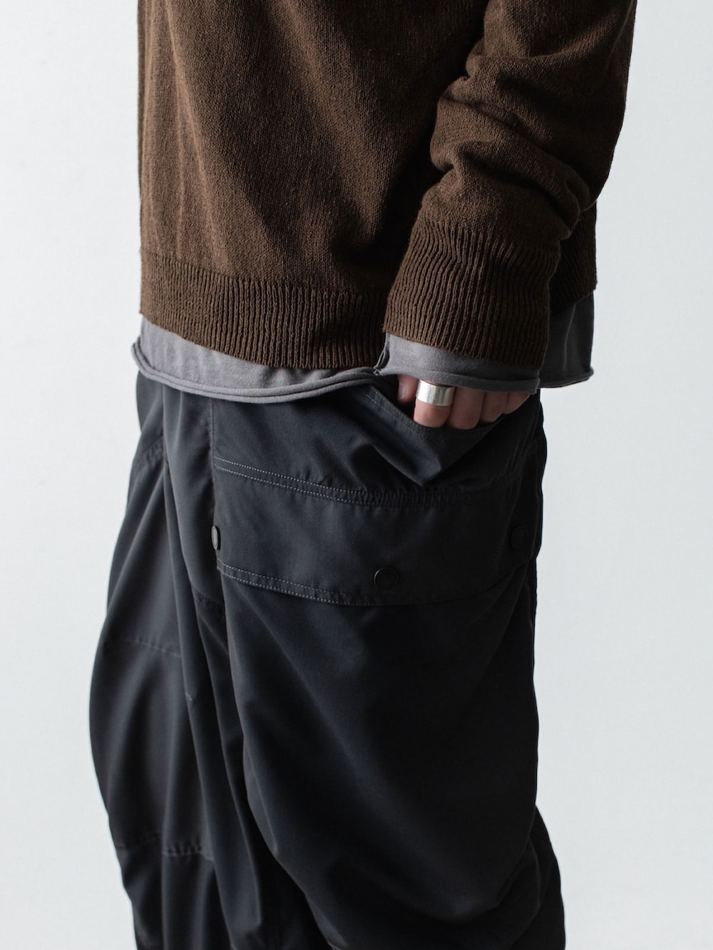 ブラウン系のニット/セーター、グレー系のTシャツ/カットソー、ブラック系のボディバッグ/ウエストポーチを着用したメンズの春コーディネートの3枚目の写真