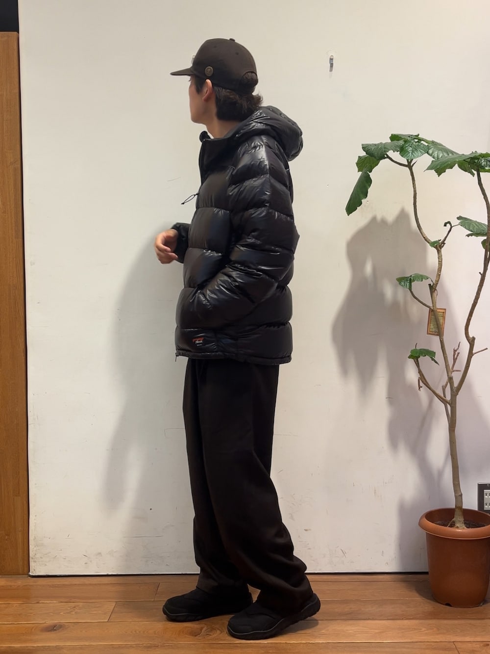 ブラウン系のその他パンツ、グリーン系のニット/セーター、ブラック系のダウンジャケット/コートを着用したメンズの秋コーディネートの2枚目の写真