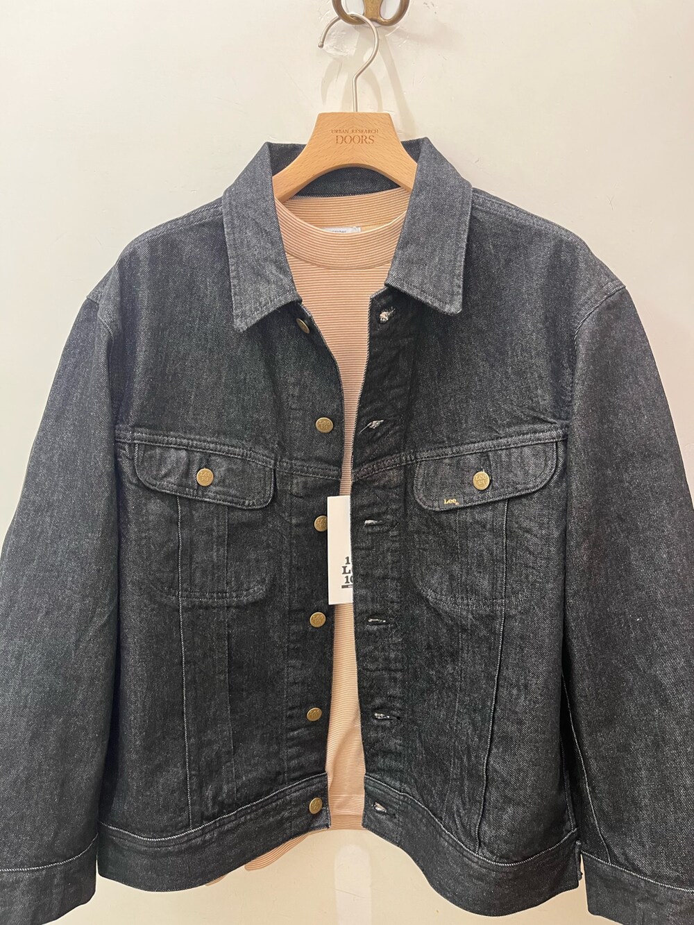 ブラック系のデニムジャケット、ベージュ系のTシャツ/カットソー、ブラック系のデニムパンツを着用したメンズの夏コーディネートの4枚目の写真