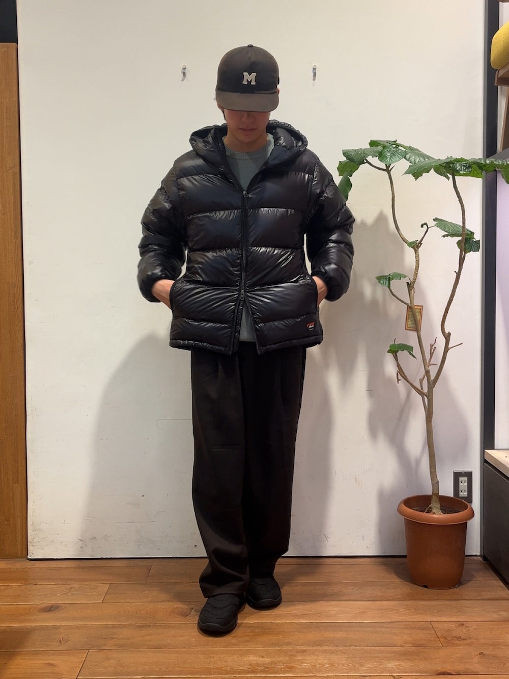 ブラウン系のその他パンツ、グリーン系のニット/セーター、ブラック系のダウンジャケット/コートを着用したメンズの秋コーディネートの6枚目の写真