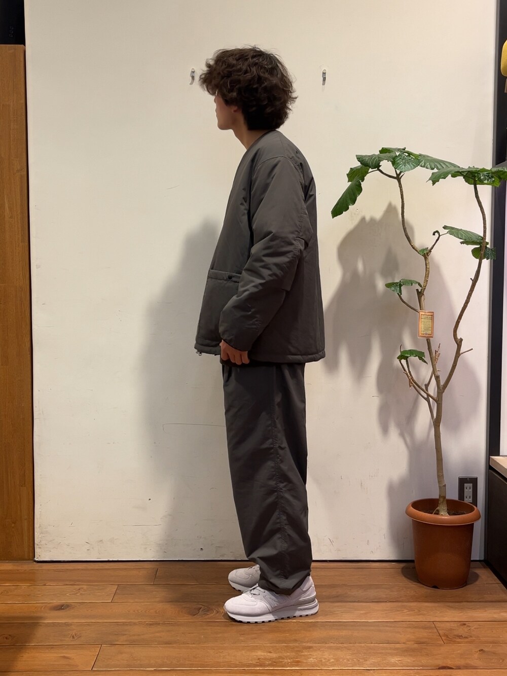 ブラウン系のニット/セーター、グレー系のダウンジャケット/コート、グレー系のその他パンツを着用したメンズの秋コーディネートの2枚目の写真