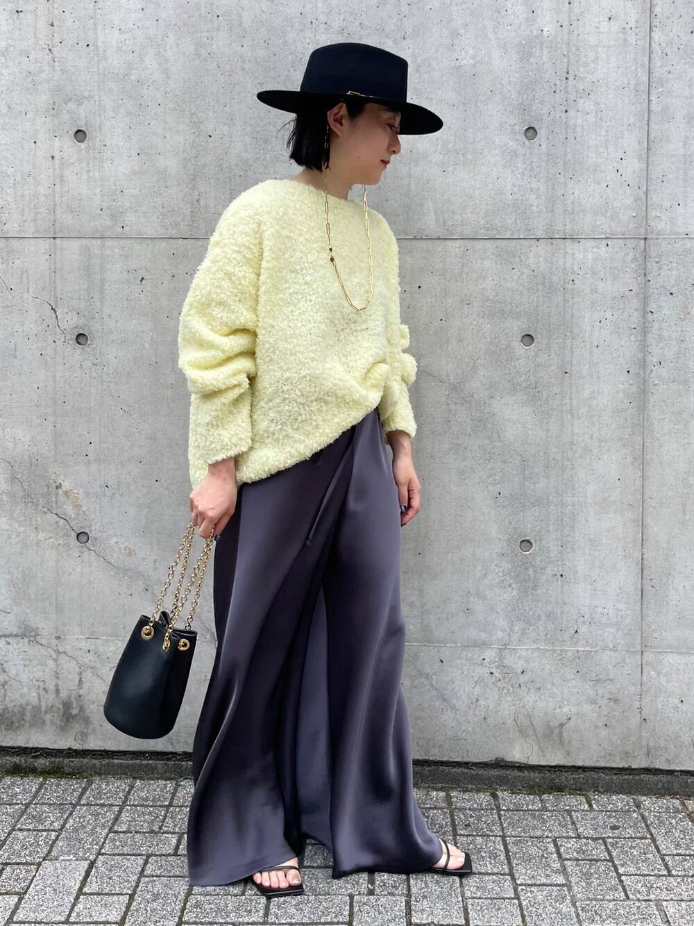 イエロー系のニット/セーター、グレー系のその他パンツを着用したレディースの夏コーディネートの3枚目の写真