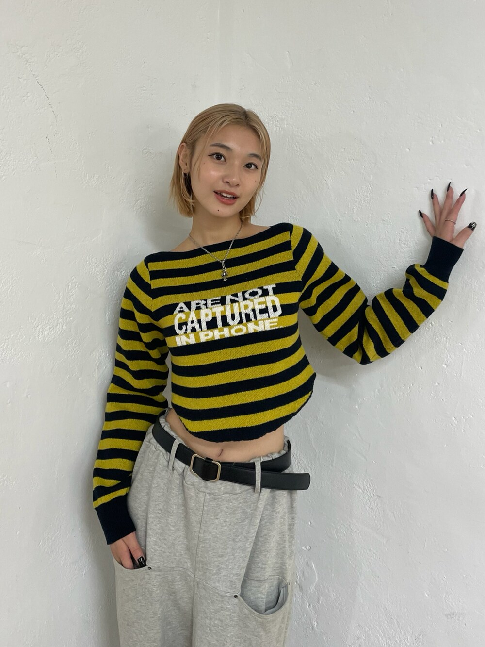 イエロー系のニット/セーター、グレー系のスウェットパンツ、ブラック系のベルトを着用したレディースの秋コーディネートの3枚目の写真