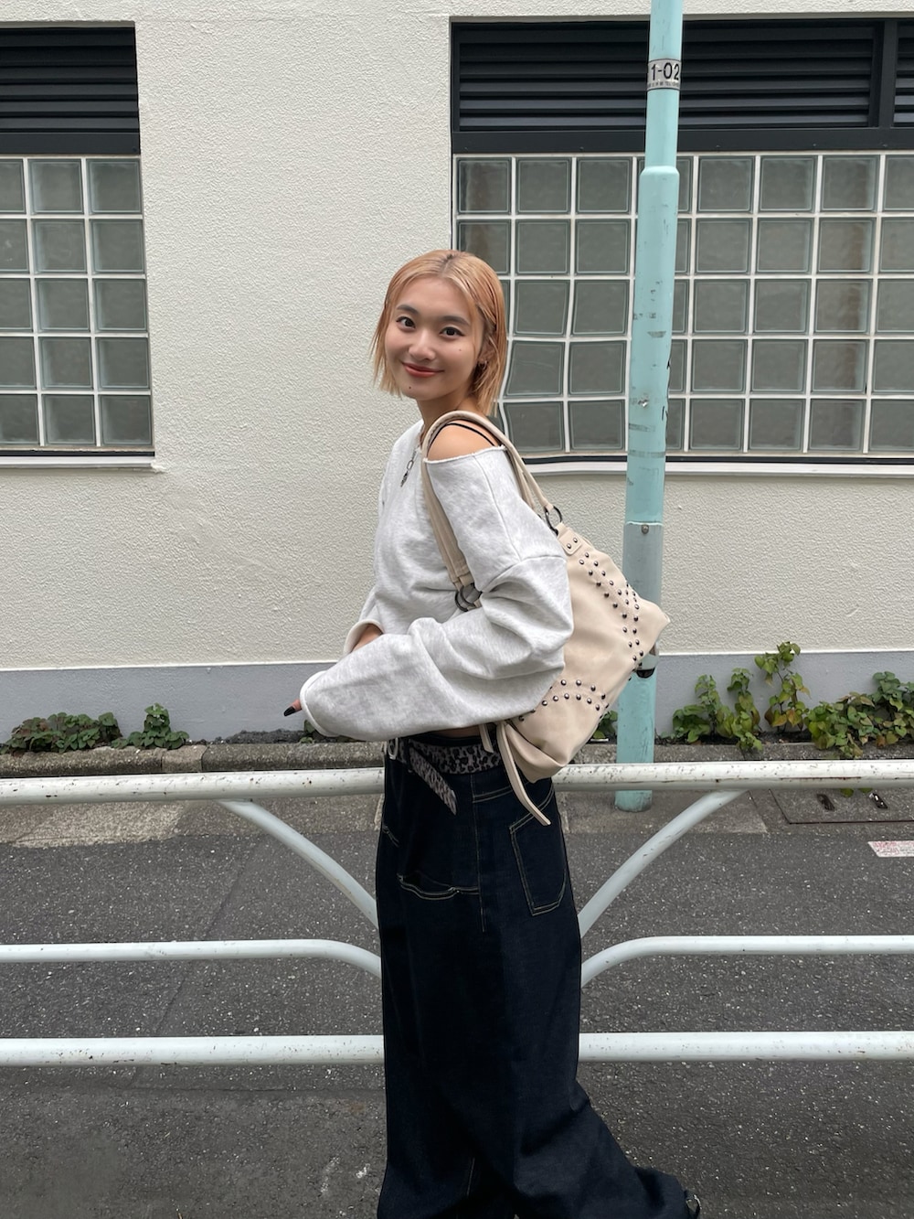 グレー系のスウェット、ブルー系のデニムパンツ、ホワイト系のショルダーバッグを着用したレディースの秋コーディネートの3枚目の写真