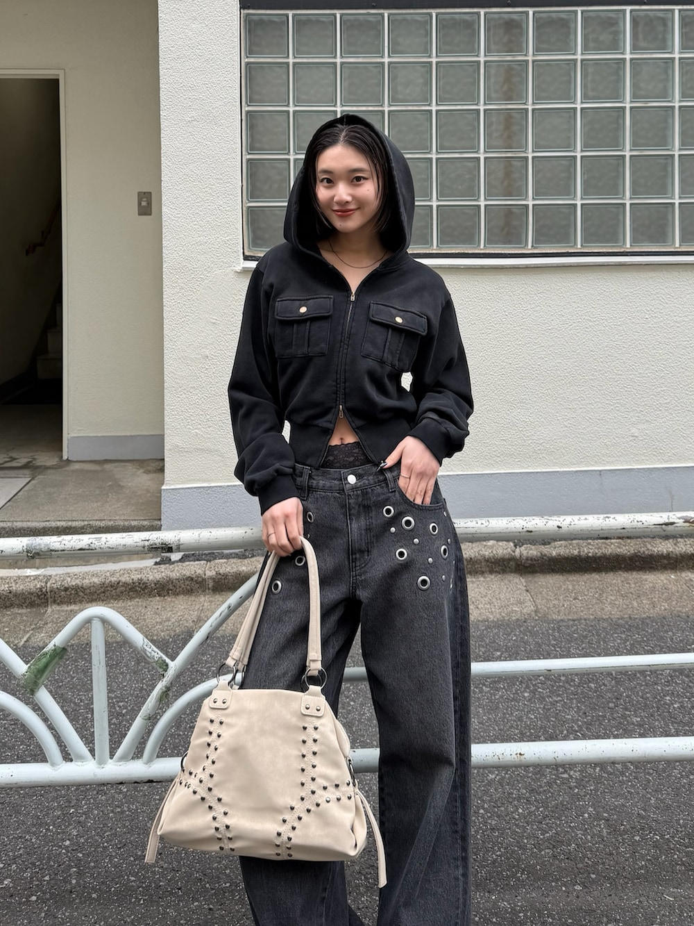 グレー系のパーカー、ブラック系のデニムパンツ、ホワイト系のショルダーバッグを着用したレディースの春コーディネートの3枚目の写真