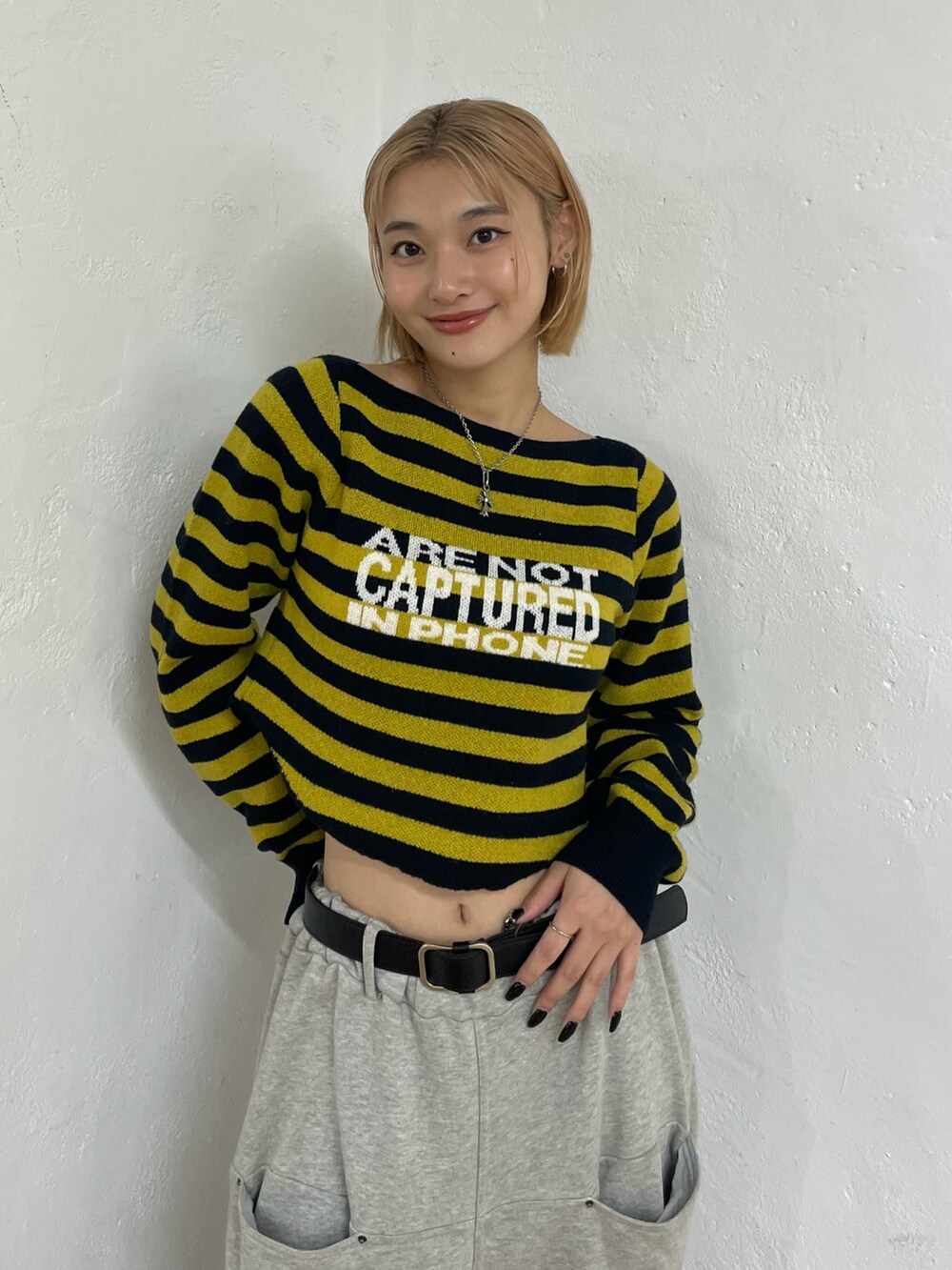 イエロー系のニット/セーター、グレー系のスウェットパンツ、ブラック系のベルトを着用したレディースの秋コーディネートの4枚目の写真