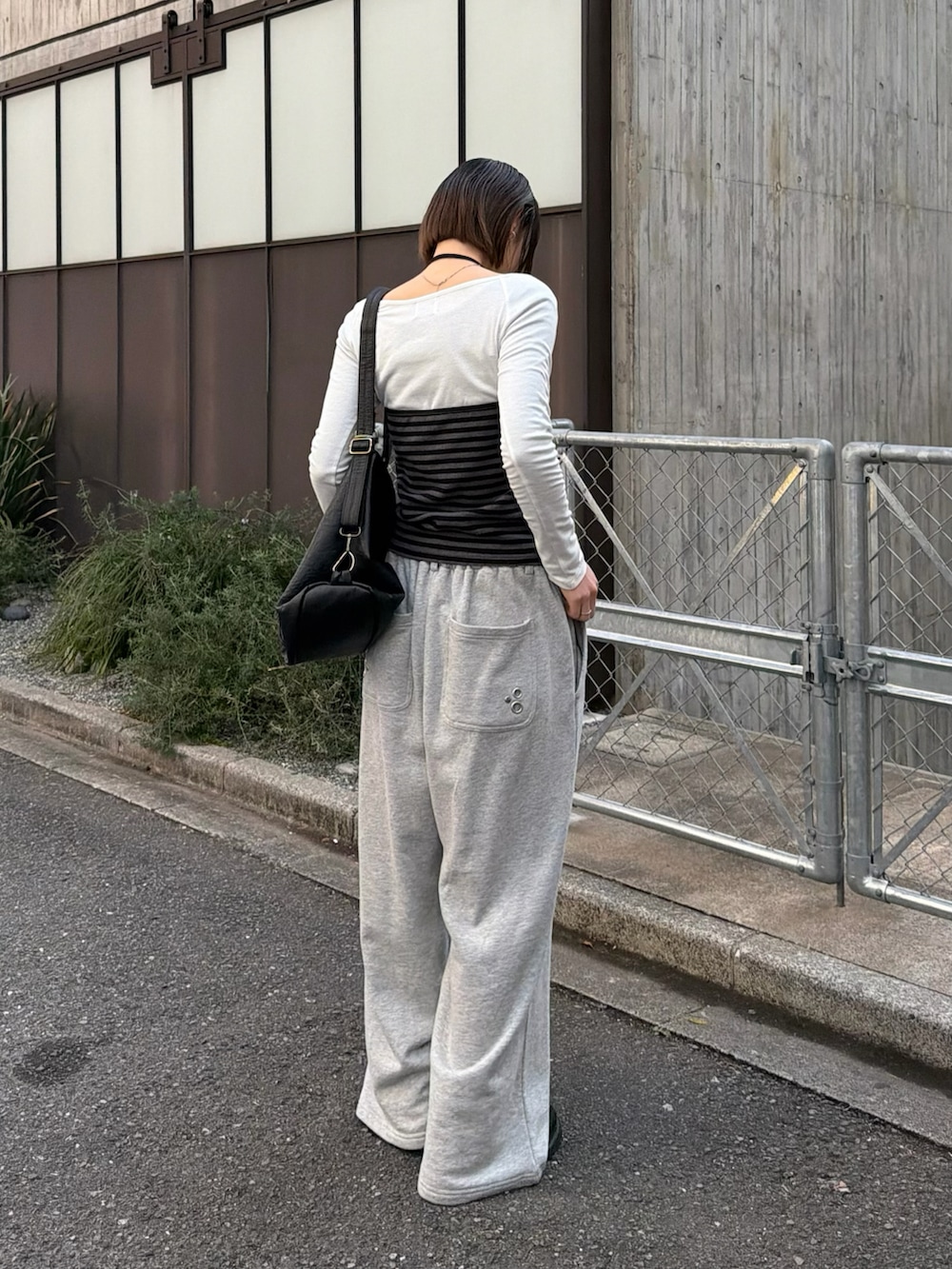 グレー系のTシャツ/カットソー、グレー系のスウェットパンツ、ブラック系のショルダーバッグを着用したレディースの冬コーディネートの2枚目の写真