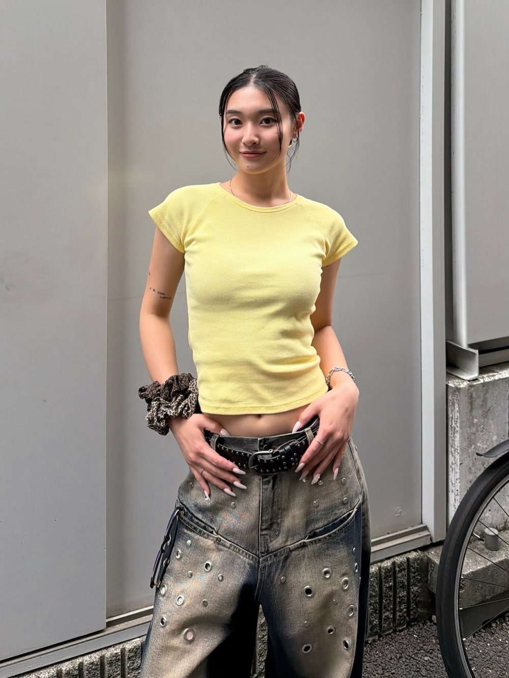 イエロー系のTシャツ/カットソー、ブルー系のデニムパンツ、ブラック系のベルトを着用したレディースの夏コーディネートの2枚目の写真