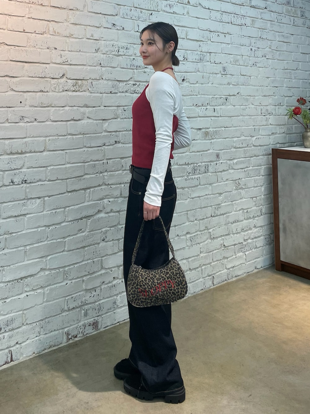 レッド系のTシャツ/カットソー、ブラウン系のショルダーバッグ、ブルー系のデニムパンツを着用したレディースの冬コーディネートの3枚目の写真