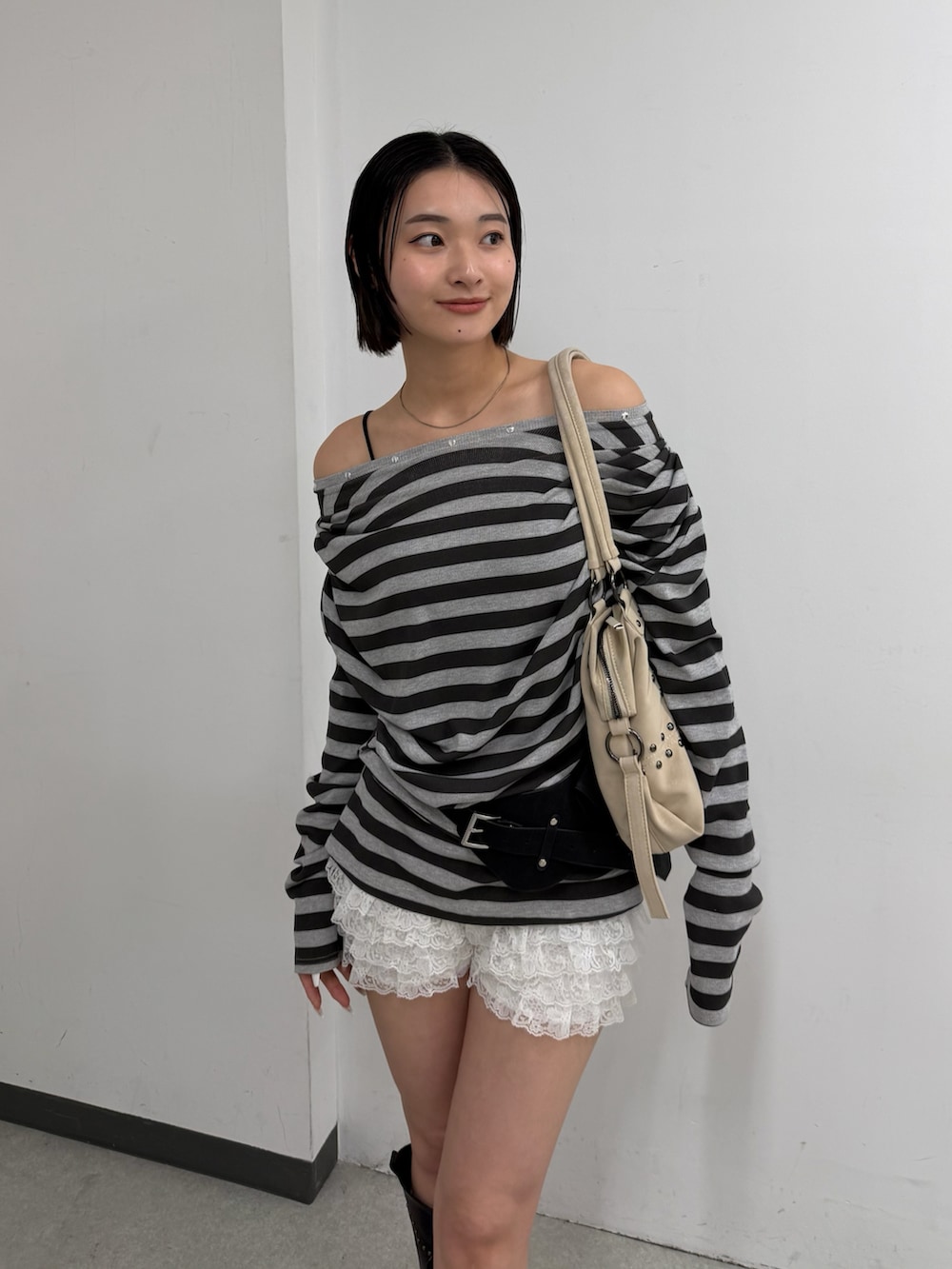 ブラック系のTシャツ/カットソー、ホワイト系のショルダーバッグ、ブラック系のブーツを着用したレディースの春コーディネートの2枚目の写真