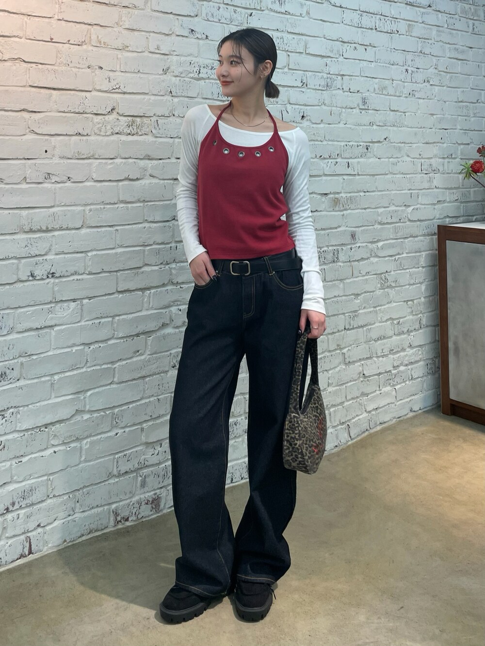 レッド系のTシャツ/カットソー、ブラウン系のショルダーバッグ、ブルー系のデニムパンツを着用したレディースの冬コーディネートの2枚目の写真