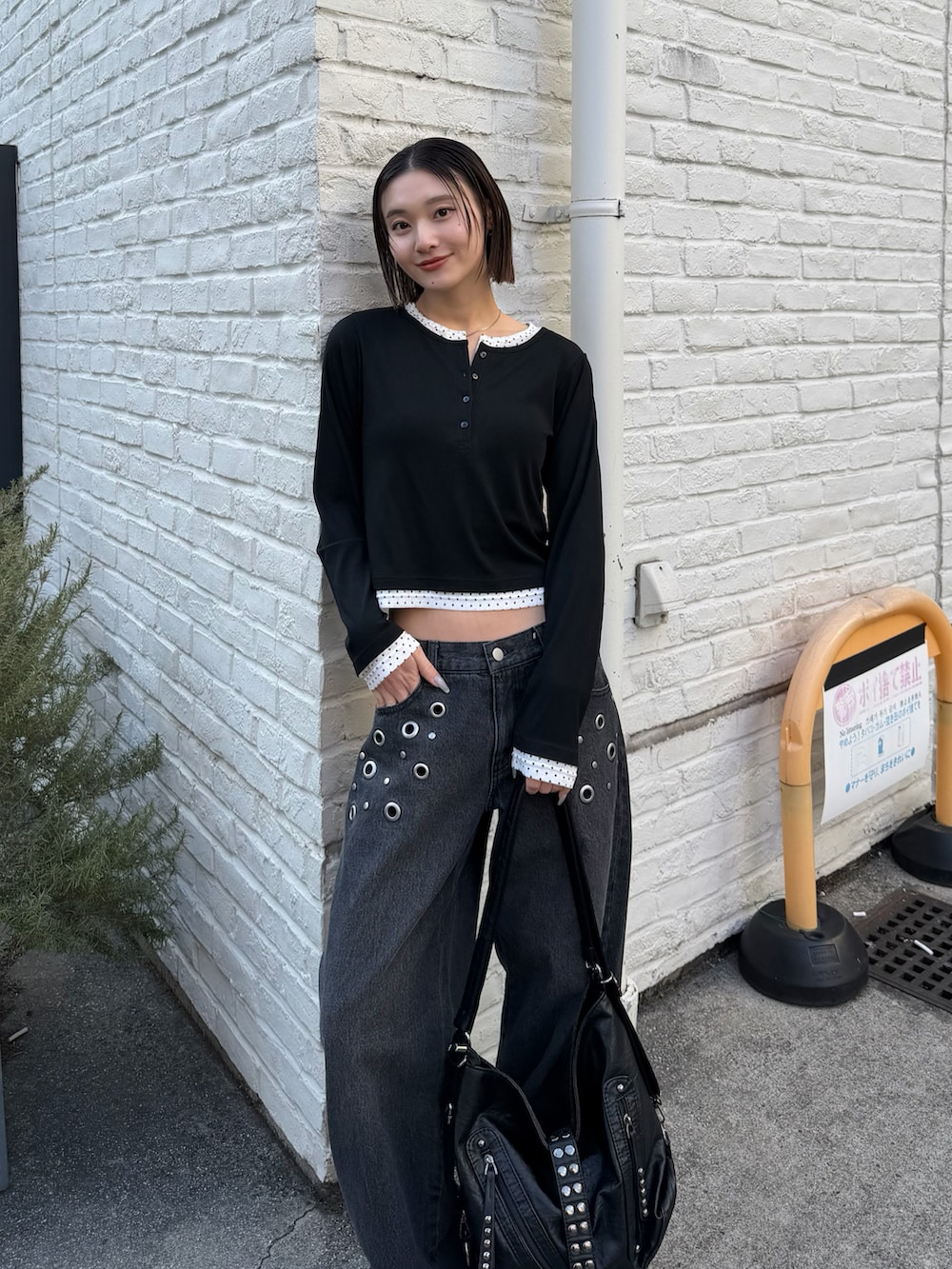 ブラック系のTシャツ/カットソー、ブラック系のショルダーバッグ、ブラック系のデニムパンツを着用したレディースの冬コーディネートの2枚目の写真