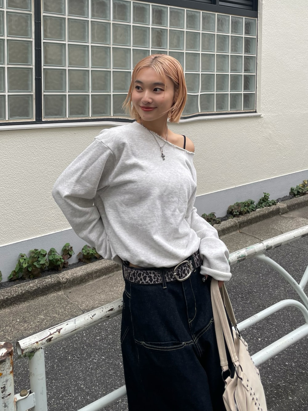 グレー系のスウェット、ブルー系のデニムパンツ、ホワイト系のショルダーバッグを着用したレディースの秋コーディネートの4枚目の写真