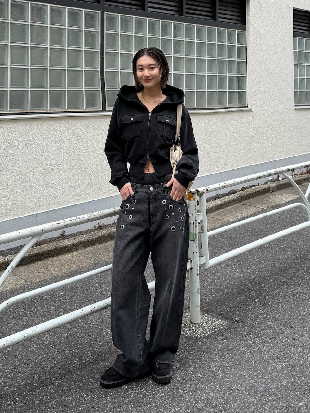 グレー系のパーカー、ブラック系のデニムパンツ、ホワイト系のショルダーバッグを着用したレディースの春コーディネートの2枚目の写真