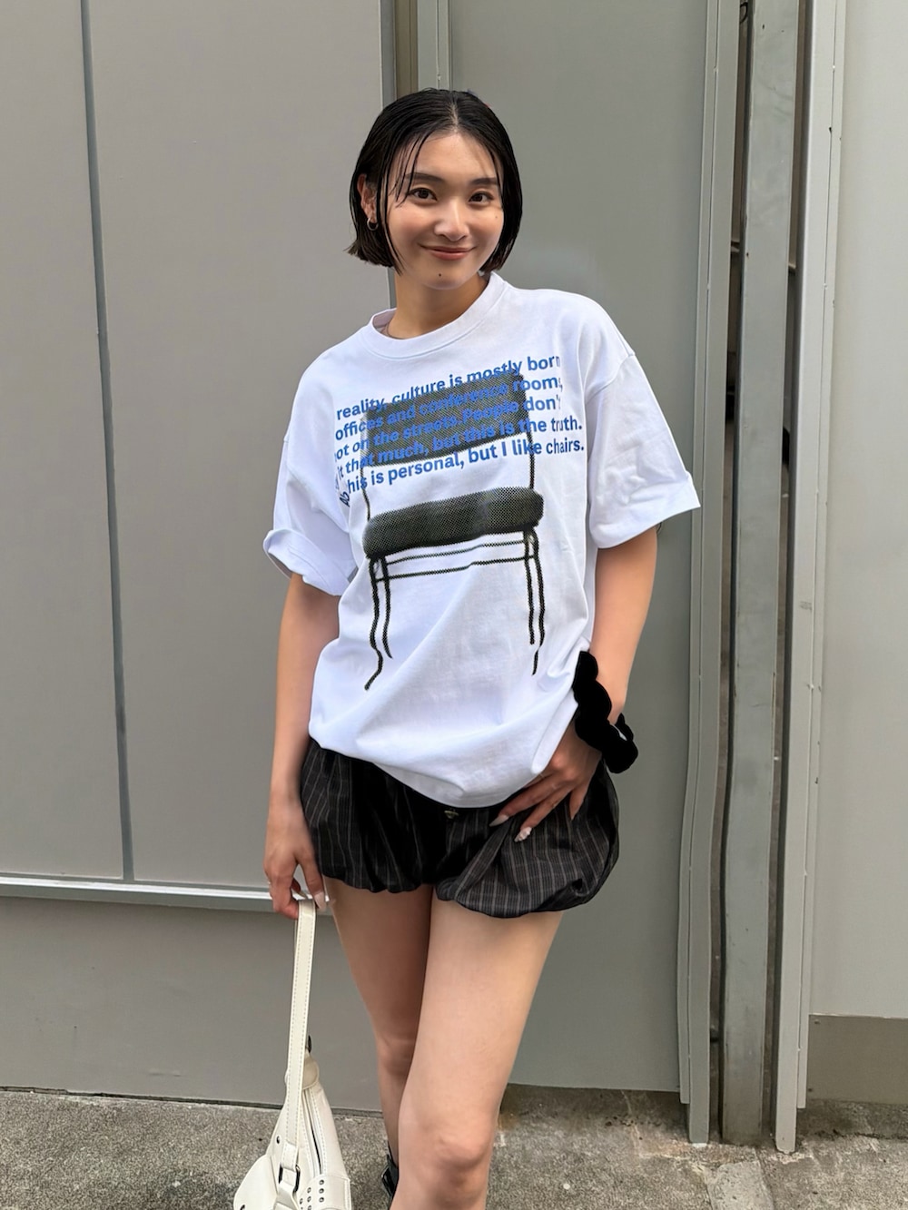 ホワイト系のTシャツ/カットソー、ブラック系のブーツ、ホワイト系のショルダーバッグを着用したレディースの夏コーディネートの2枚目の写真