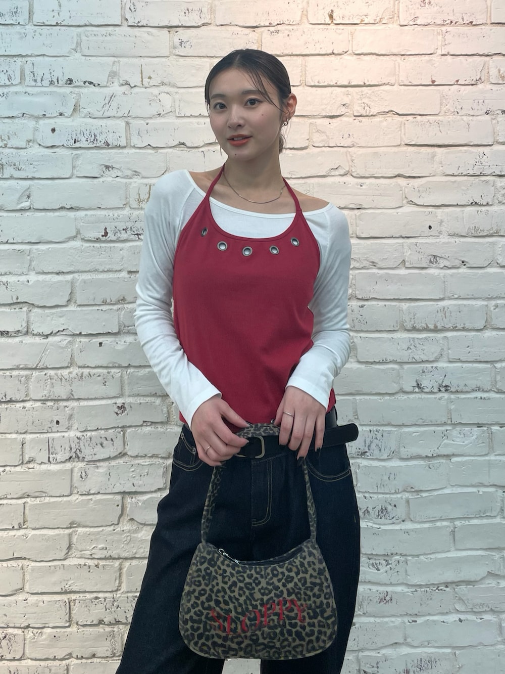 レッド系のTシャツ/カットソー、ブラウン系のショルダーバッグ、ブルー系のデニムパンツを着用したレディースの冬コーディネートの4枚目の写真
