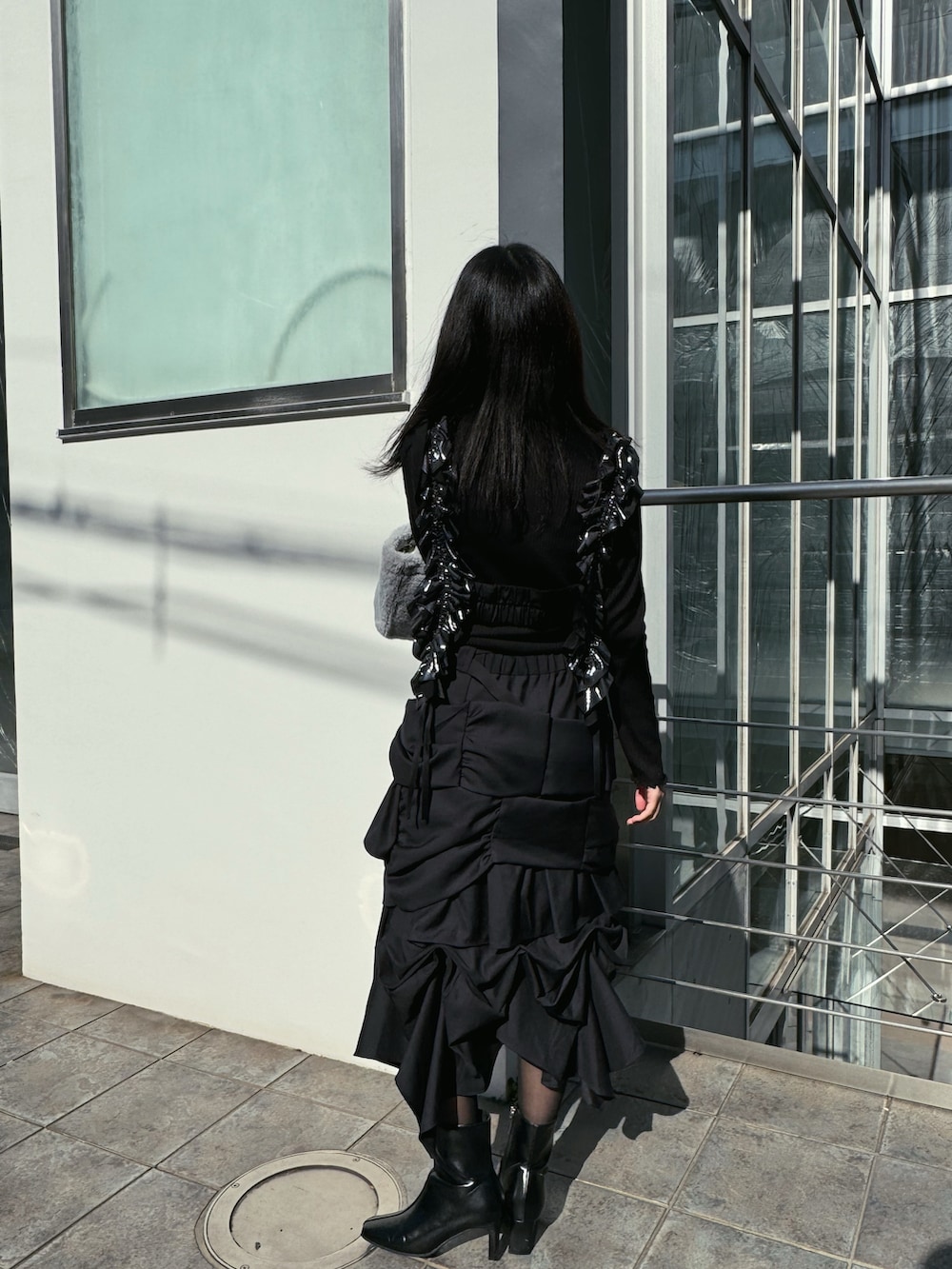 ブラック系のスカート、ブルー系のトートバッグ、ブラック系のブーツを着用したレディースの冬コーディネートの2枚目の写真