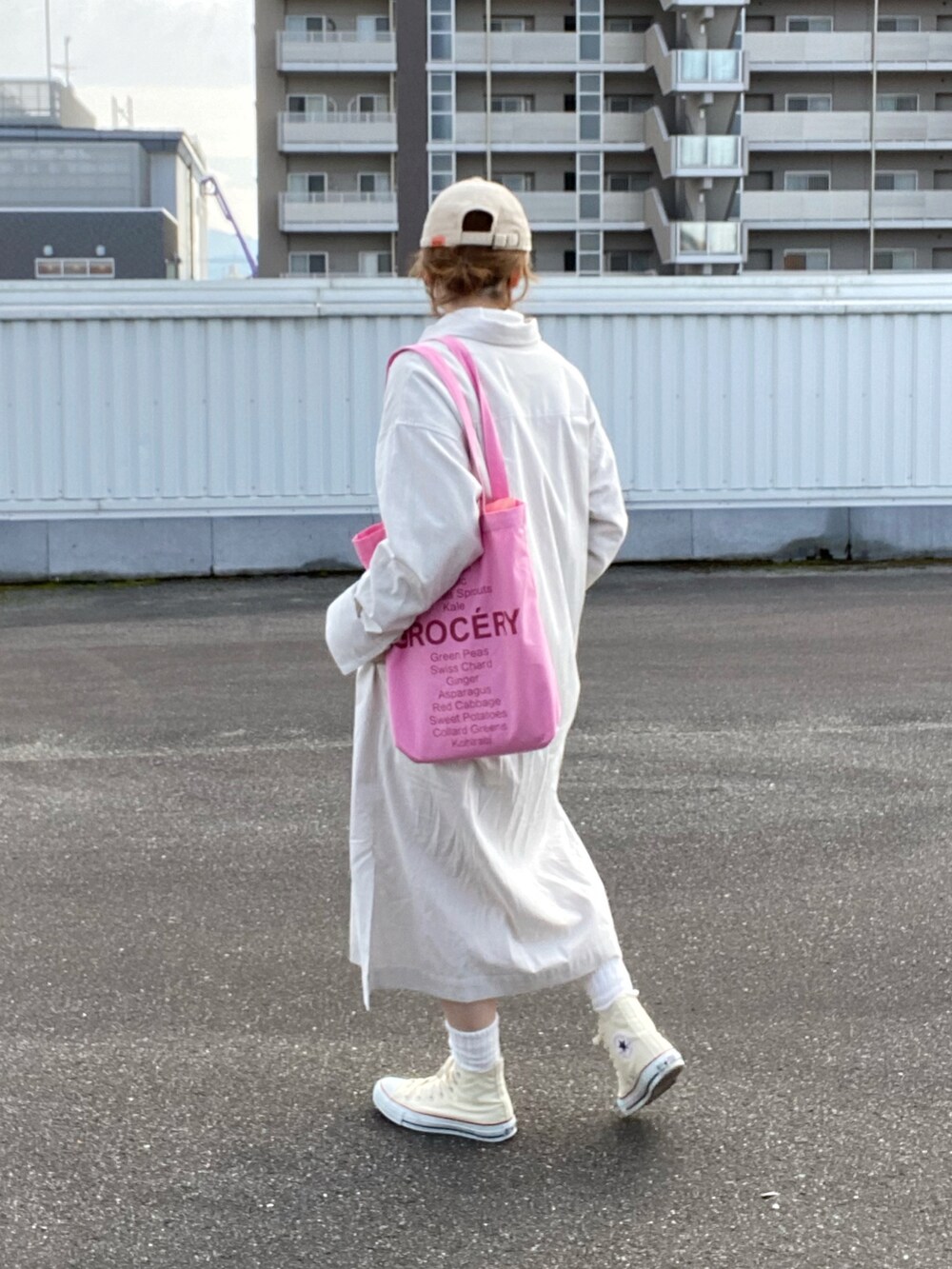 ベージュ系のワンピース、ホワイト系のスニーカー、ピンク系のトートバッグを着用したレディースの冬コーディネートの2枚目の写真