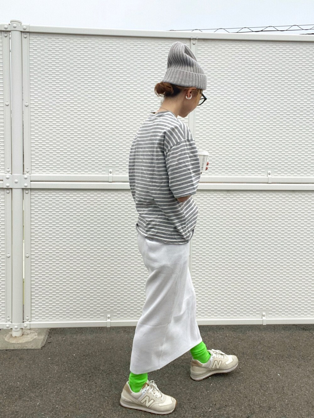 グレー系のTシャツ/カットソー、ホワイト系のスカート、ホワイト系のスニーカーを着用したレディースの春コーディネートの2枚目の写真