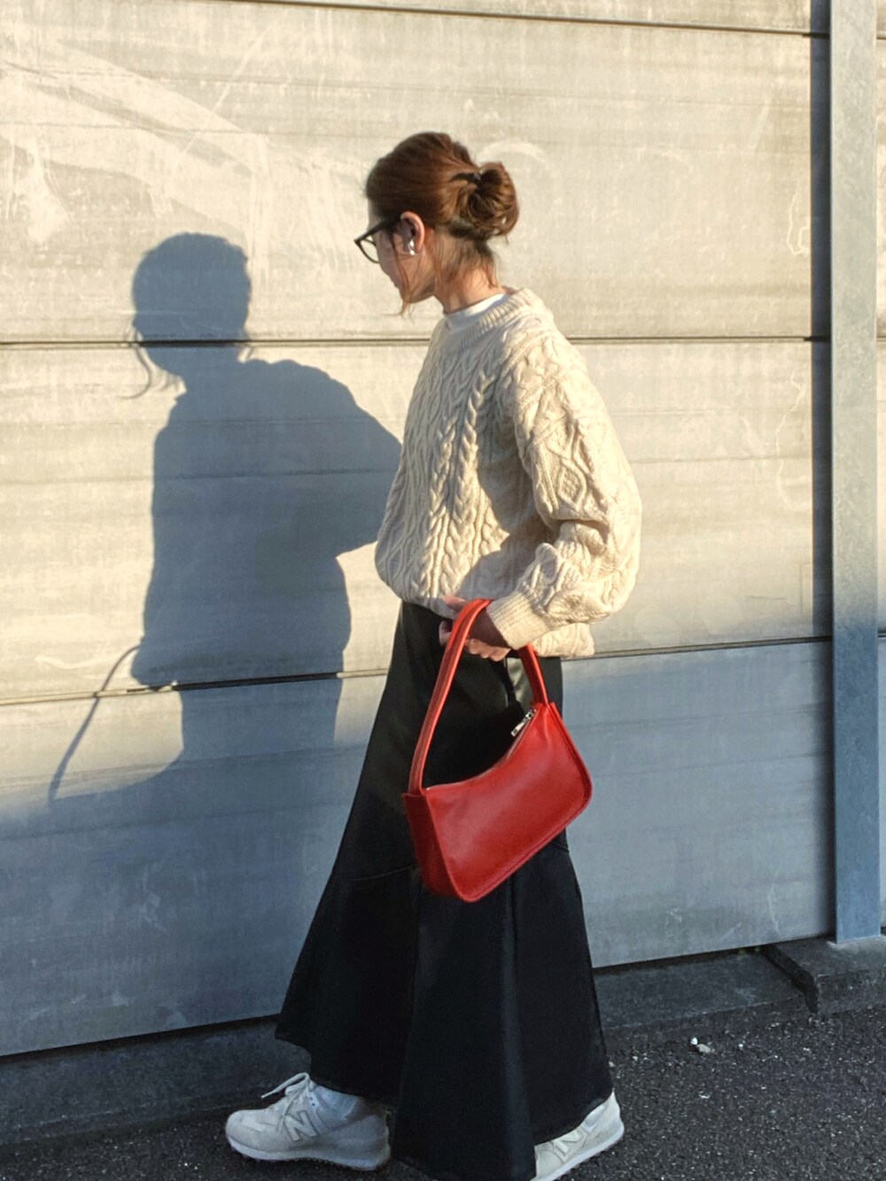 ホワイト系のニット/セーター、ブラック系のスカート、オレンジ系のショルダーバッグを着用したレディースの秋コーディネートの2枚目の写真