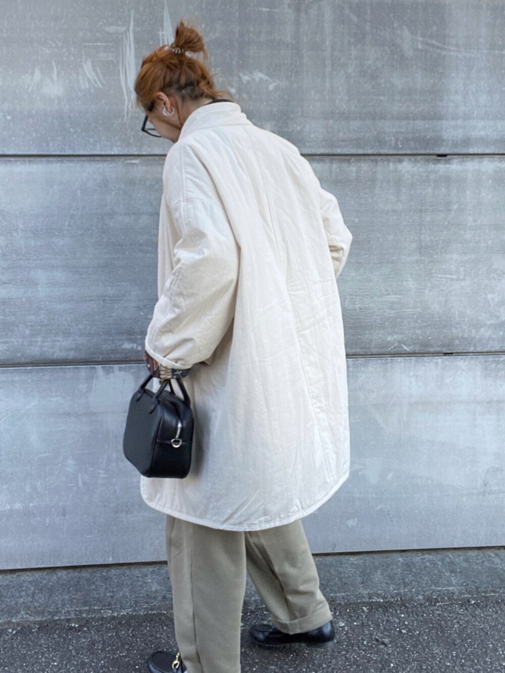 ブラック系のスウェット、ホワイト系のブルゾン、ブラック系のボストンバッグを着用したレディースの冬コーディネートの3枚目の写真